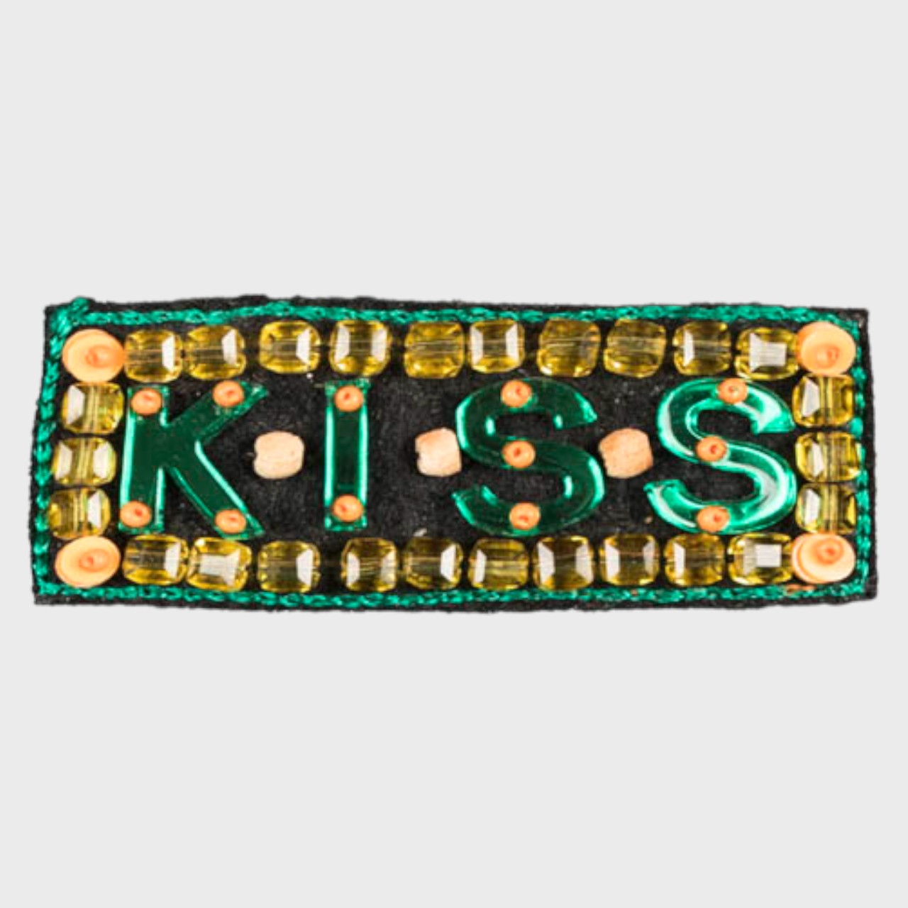 An embroidered Brooch with yellow and green details and embroidered KISS in the center. 