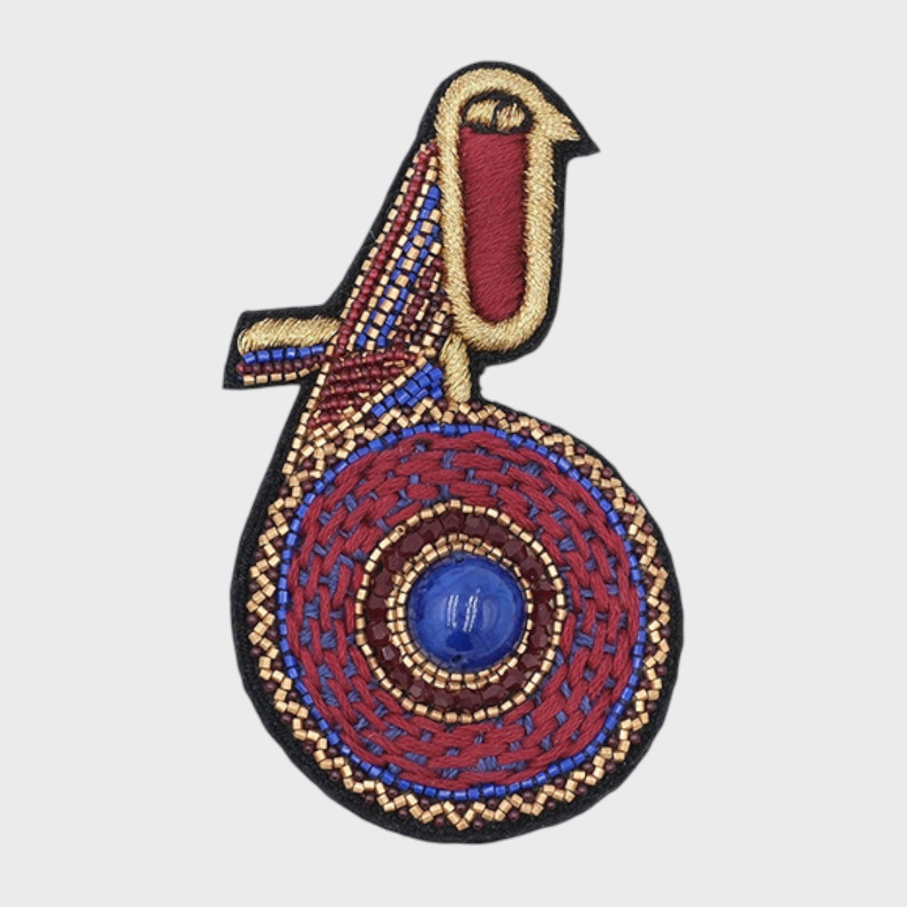 An embroidered brooch representing a purple kiwi bird with burgundy details. 