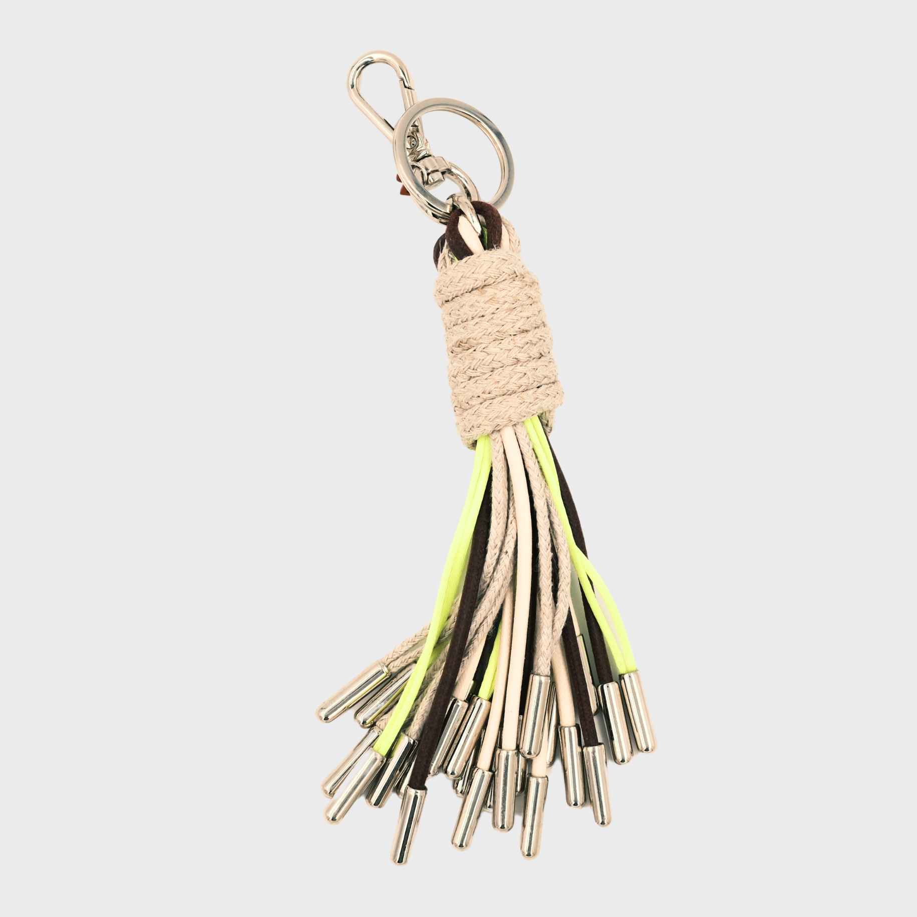 A keychain tassel with a silver metal clasp and ring, featuring a beige woven wrap and multiple hanging cords in brown, white, and neon yellow.