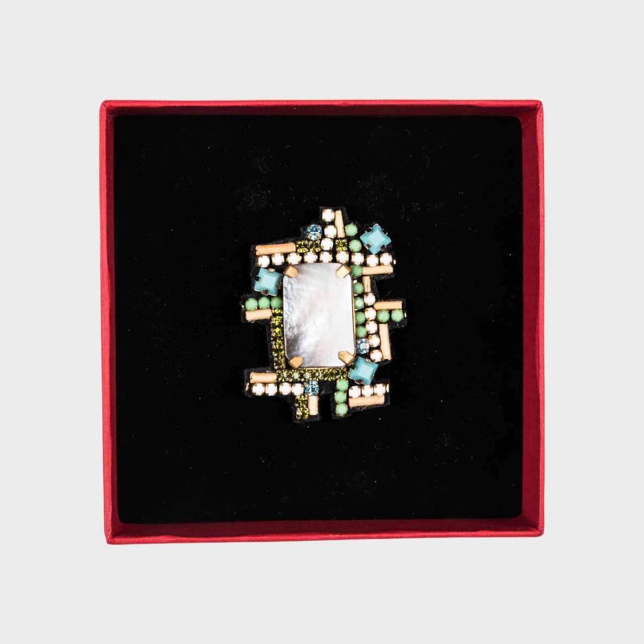 An embroidered brooch symbolizing a lake in a box. 
