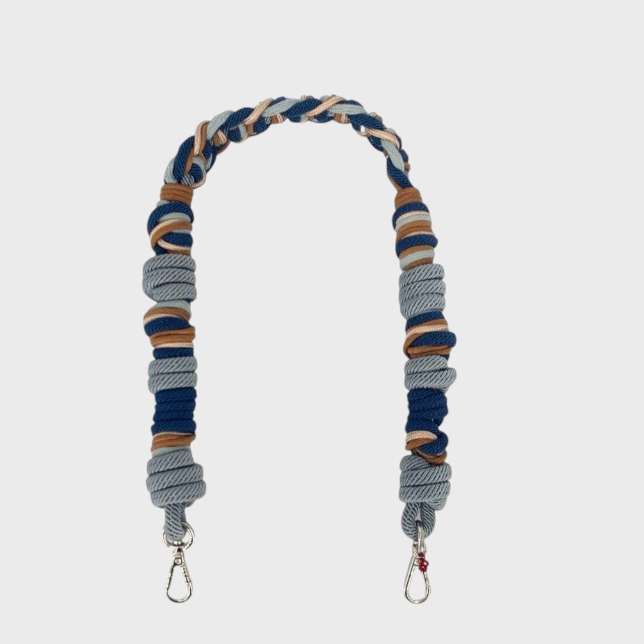 Multicolored braided macramé strap in light blue, dark blue and brown with silver metal clasps on a light gray background.