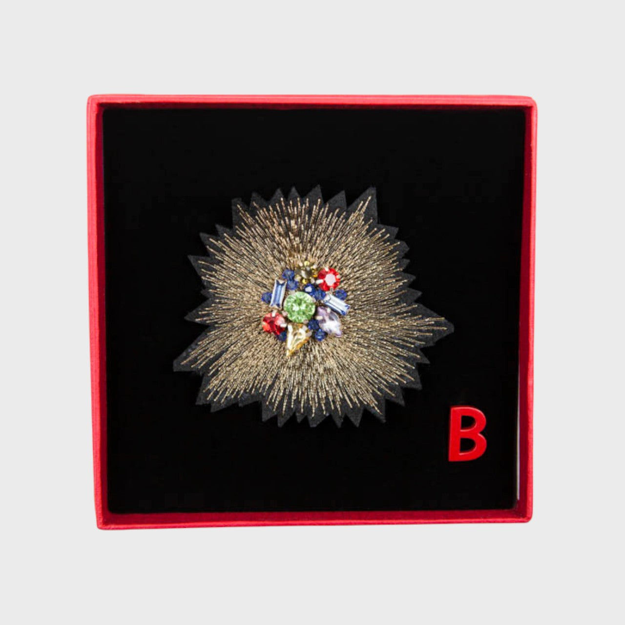An embroidered brooch representing a golden sunset in a box. 