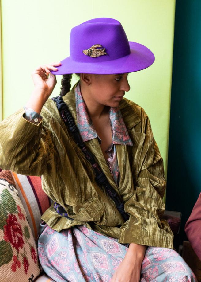 A model wearing a lucky bord golden brooch on a hat. 