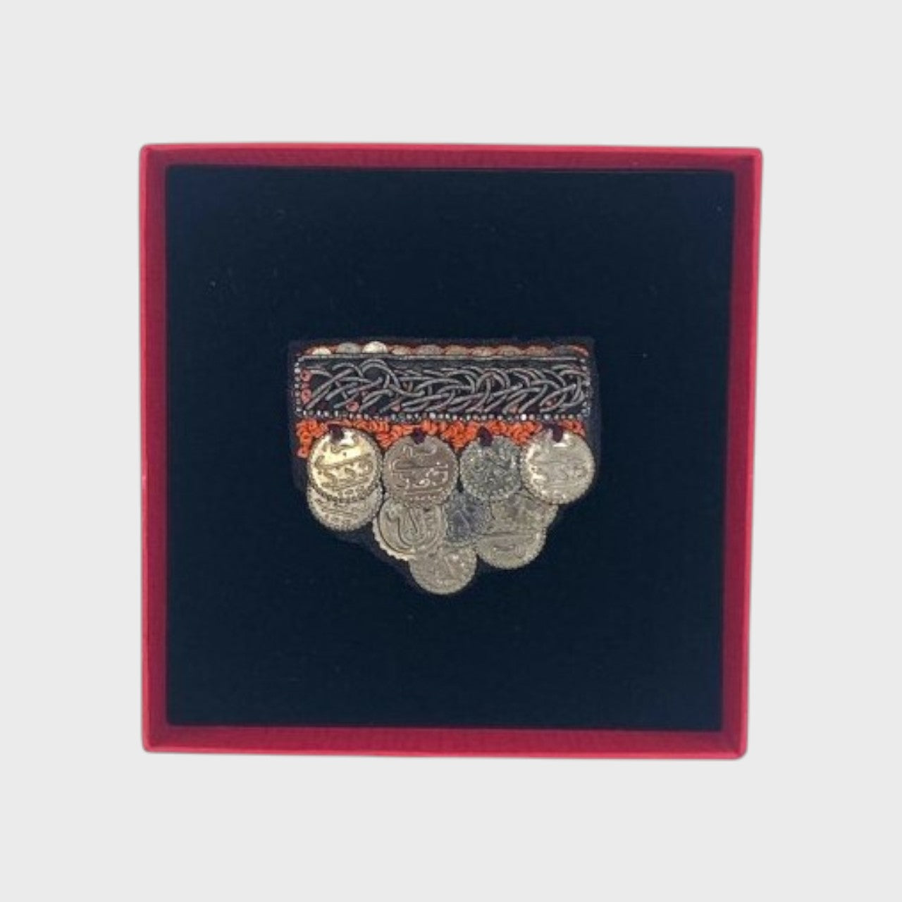 An embroidered brooch representing medals in a box. 