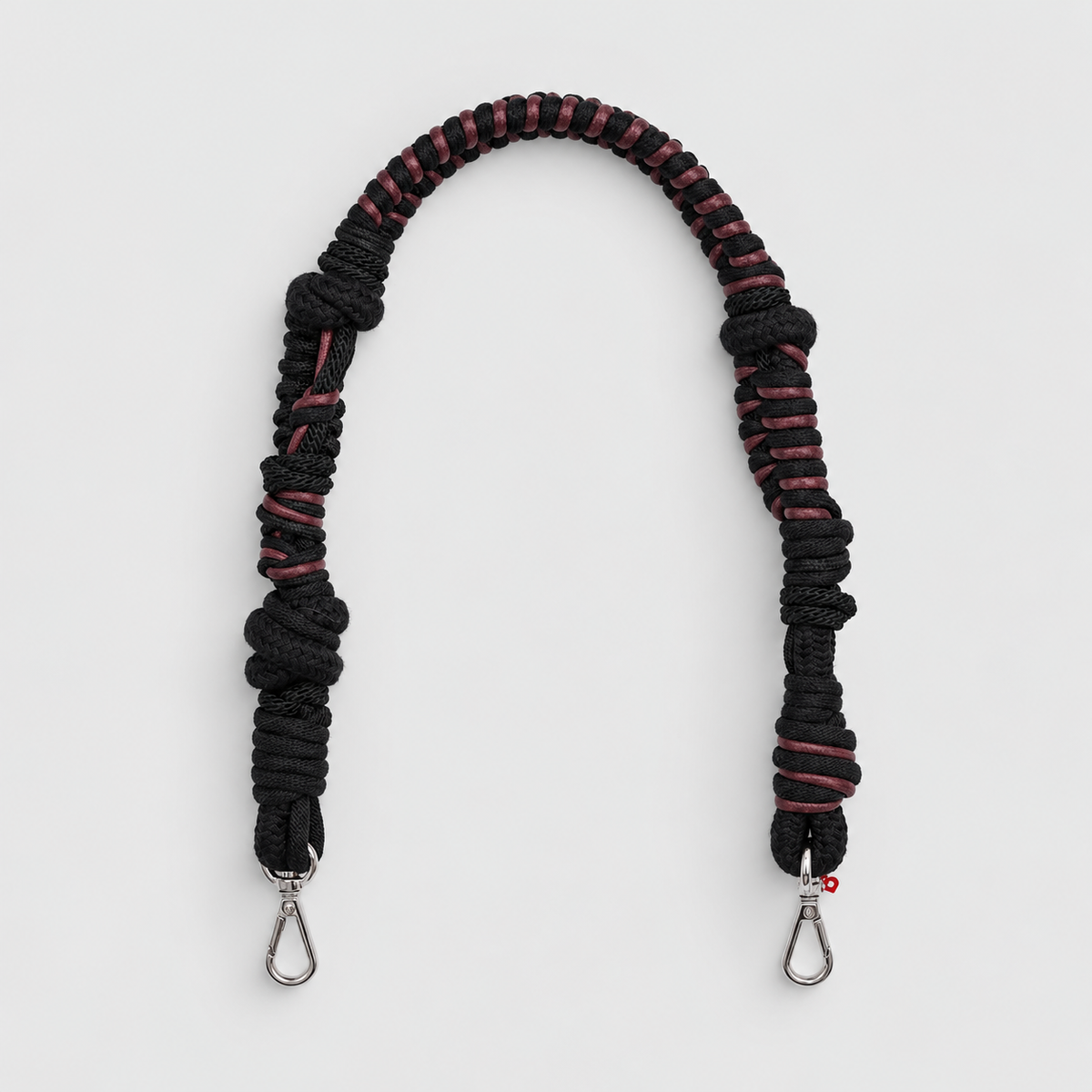 Black and red braided macramé bag strap on a light gray background