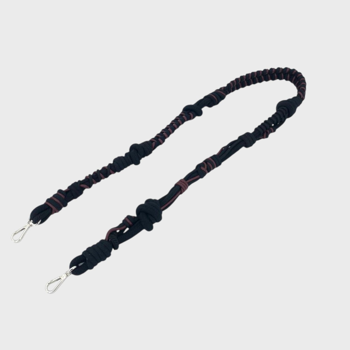 Black and red braided bag strap on a light gray background