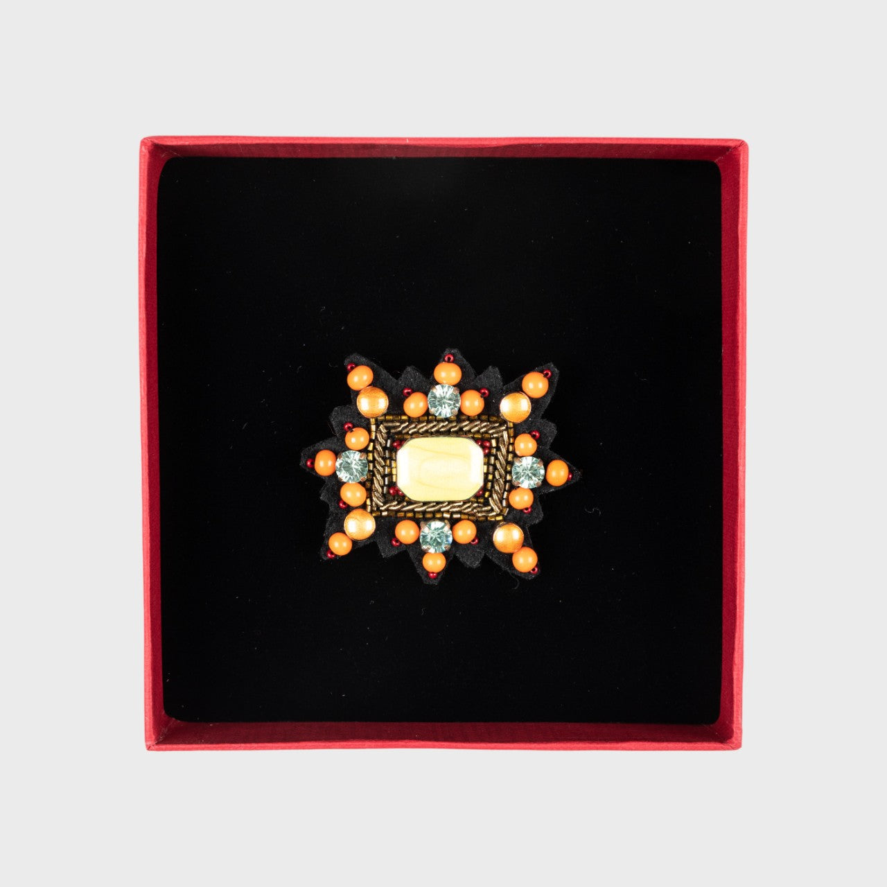 An orange Mizar star brooch in a box. 