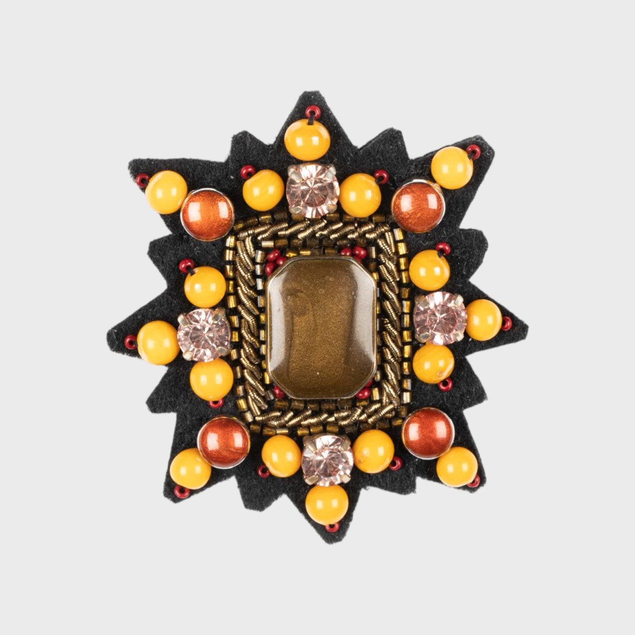 An embroidered brooch representing a Mizar star with yellow and orange details. 
