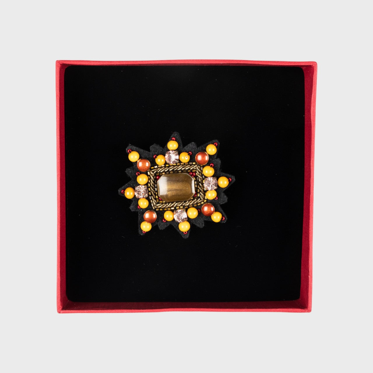 An embroidered brooch representing a yellow Mizar star in a box. 