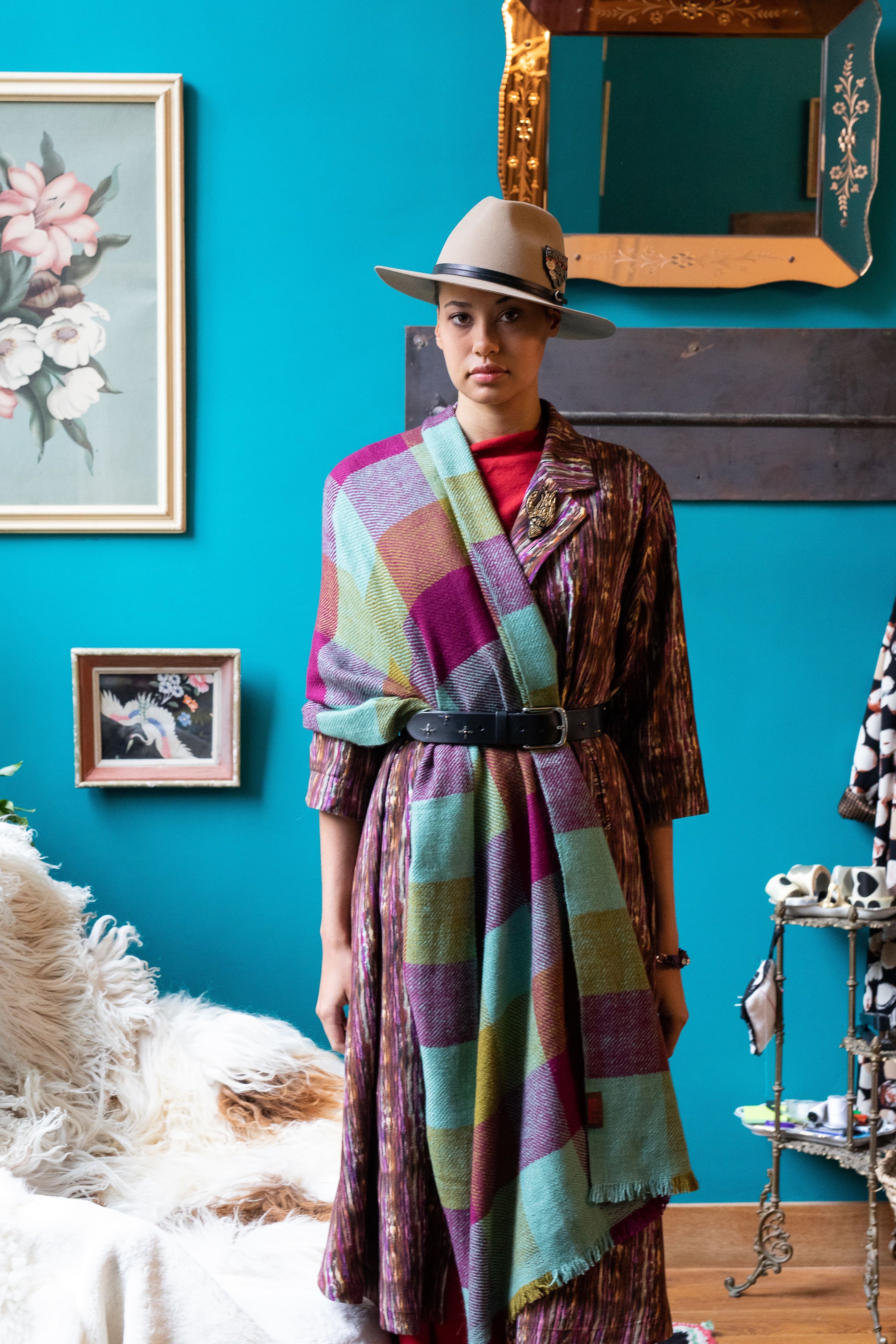 Model wearing the black leather belt on a colourful outfit inside a living room.