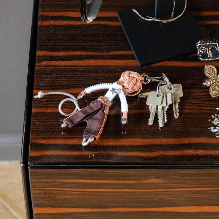 Cowboy bag charm presented on a brown wooden table attached to keys.