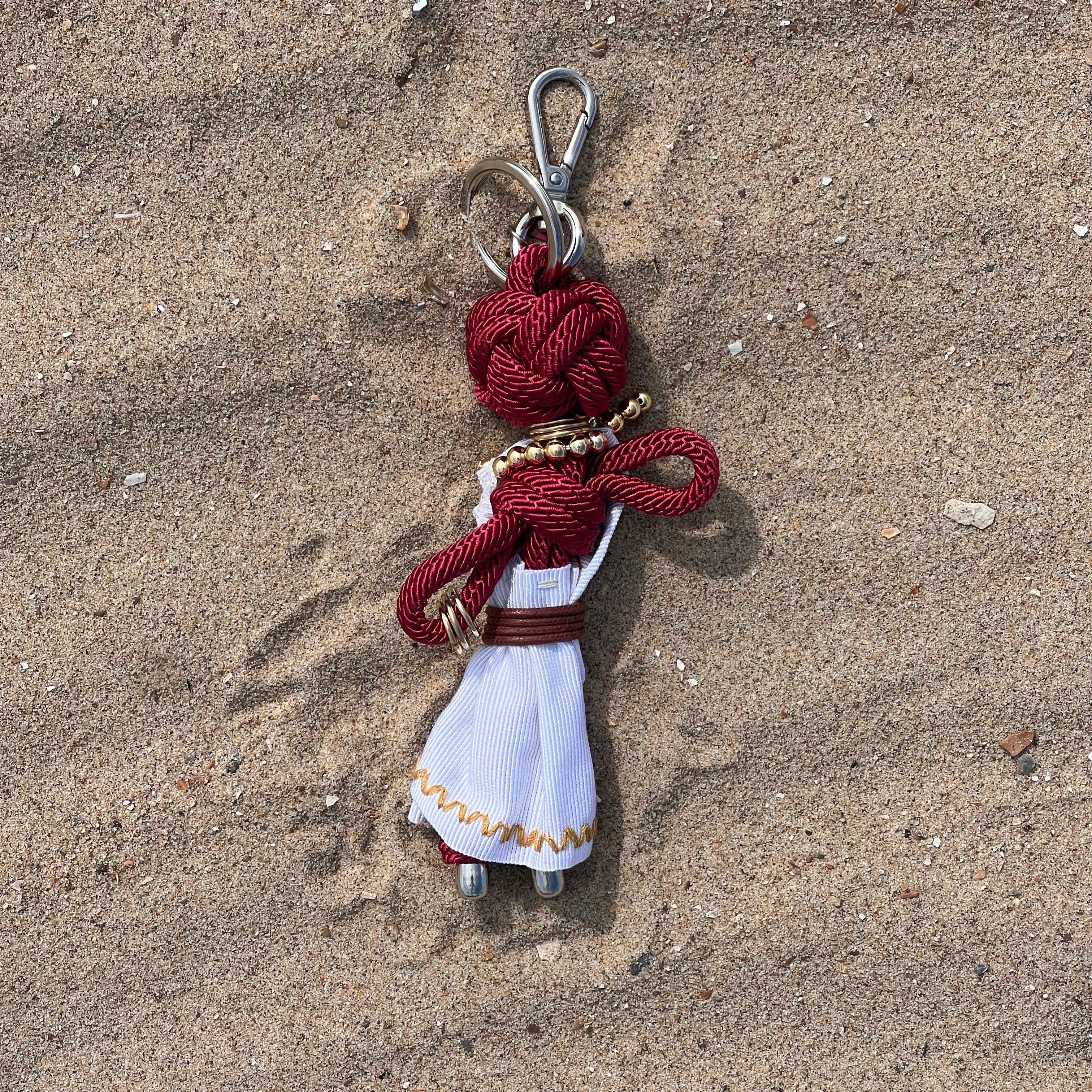 Deesse bag charm shown in the sand on a sunny day