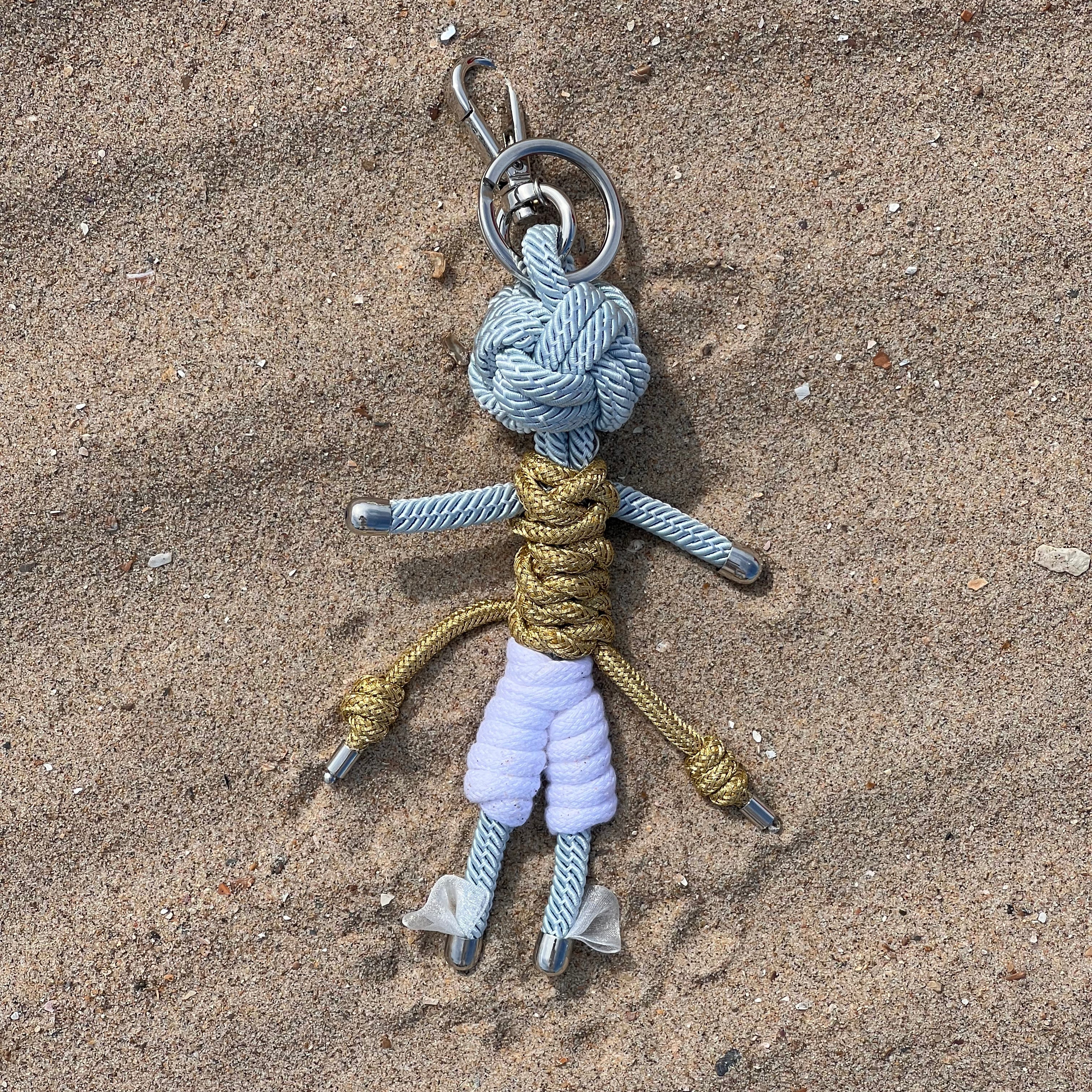 Hermes bag charm shown in the sand on a sunny day.