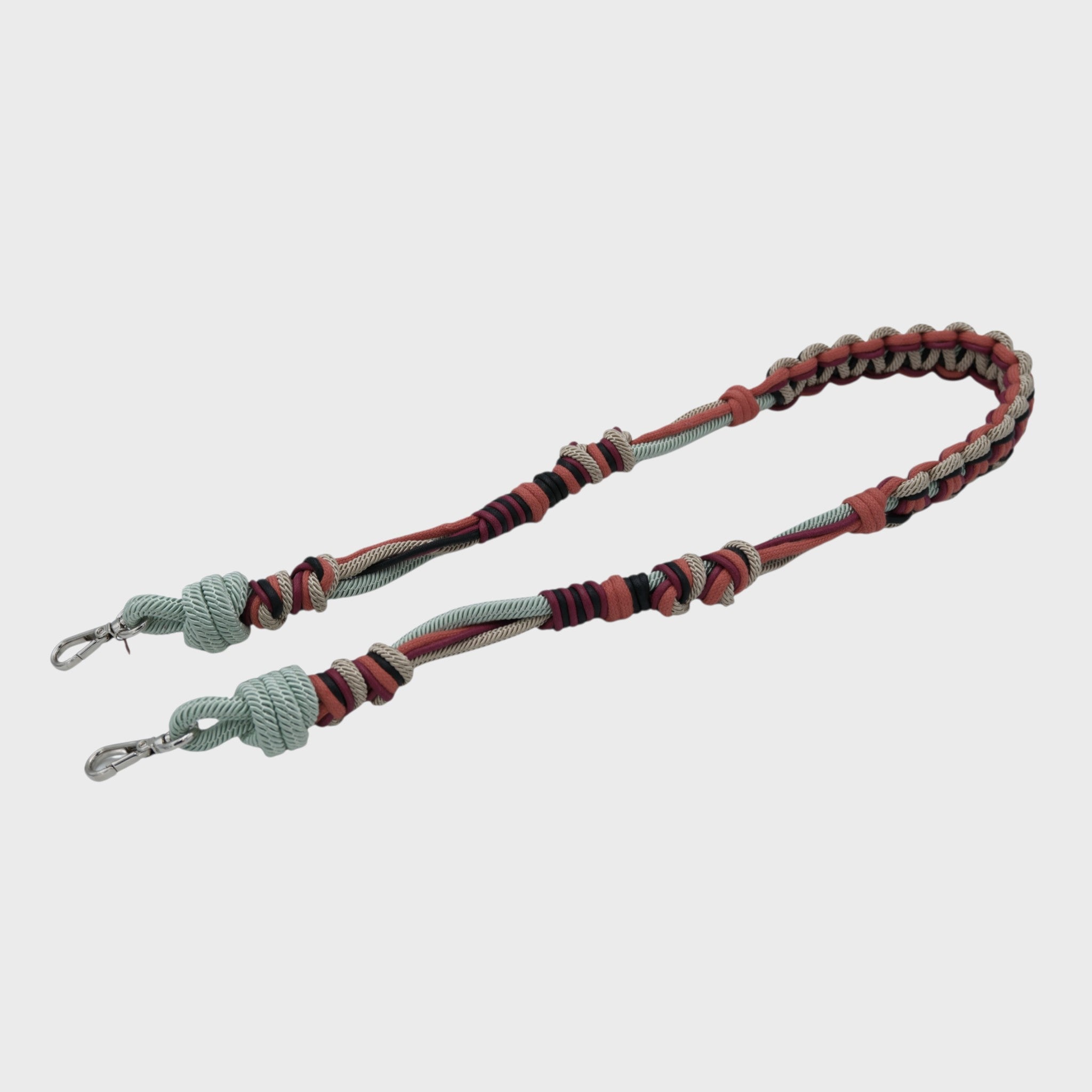 Multicolored braided macramé bag strap in soft light blue, soft pink, and burgundy shown on a light gray background.