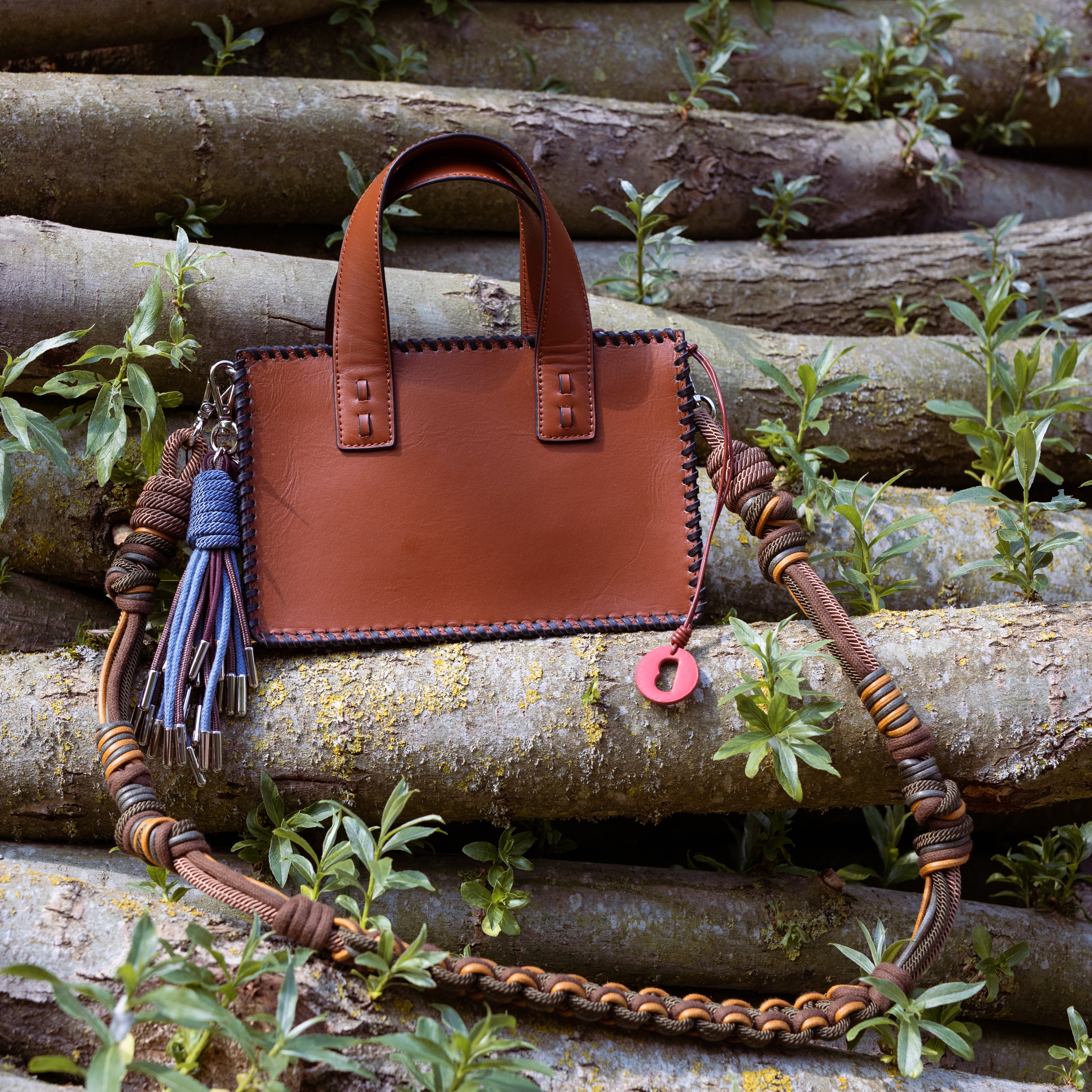 The Brown leather Maori Handbagwith the yellow and green strap put on trees. 