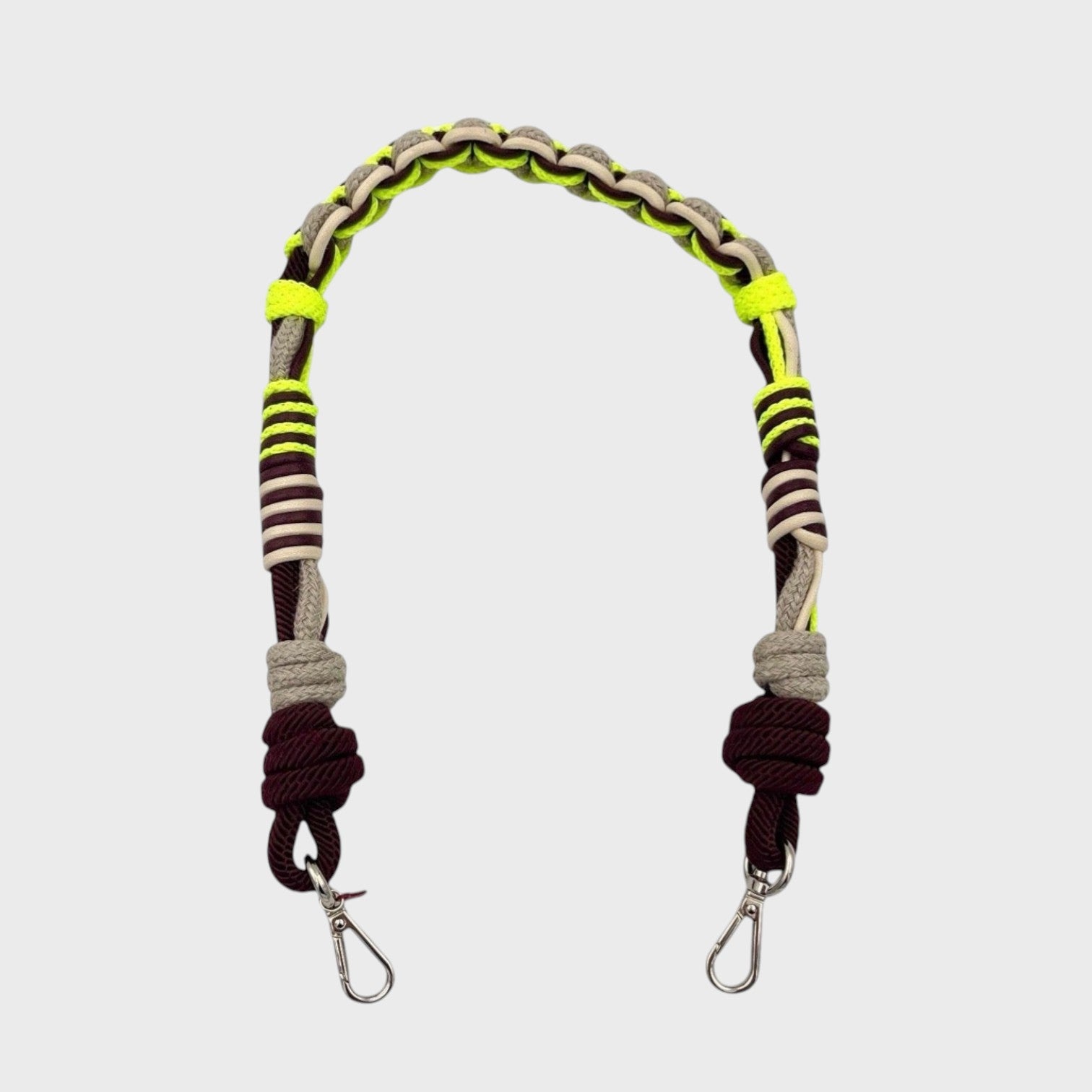 Multicolored braided macramé bag strap in neon yellow, beige, and brown shown on a light gray background.
