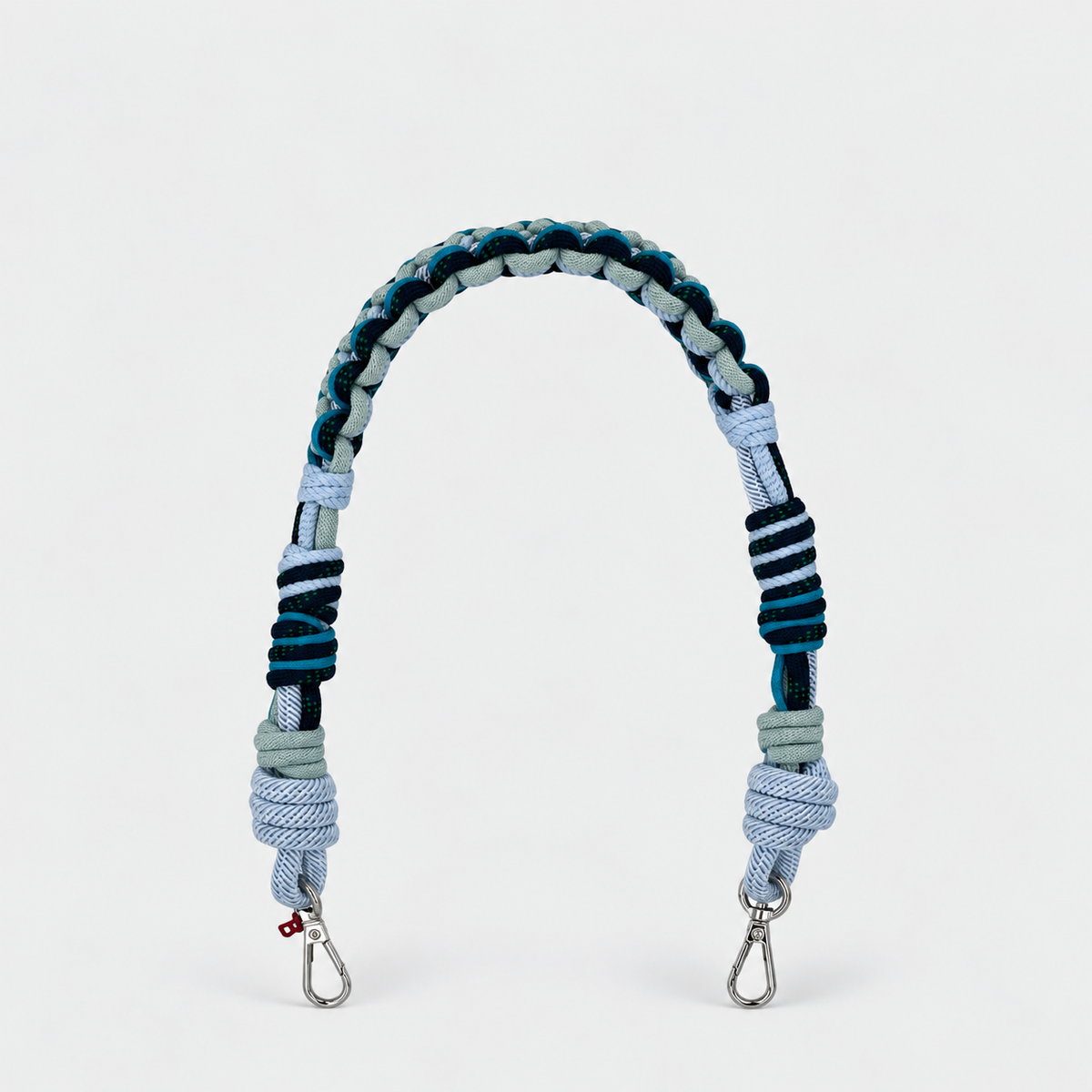 A braided macramé bag strap with a light blue and dark teal pattern, featuring silver metal snap hooks at the ends.