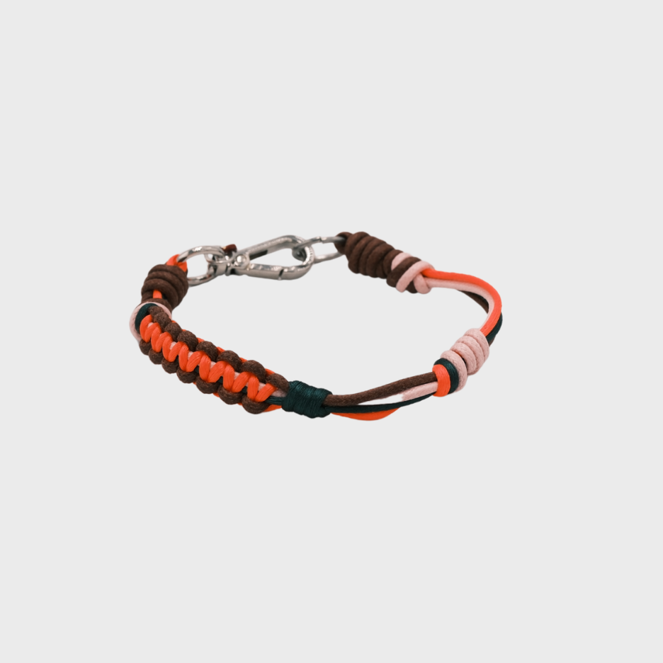 A thin braided bracelet with neon orange, black,  dark green and brown macramé, featuring a silver metal  clasp. 