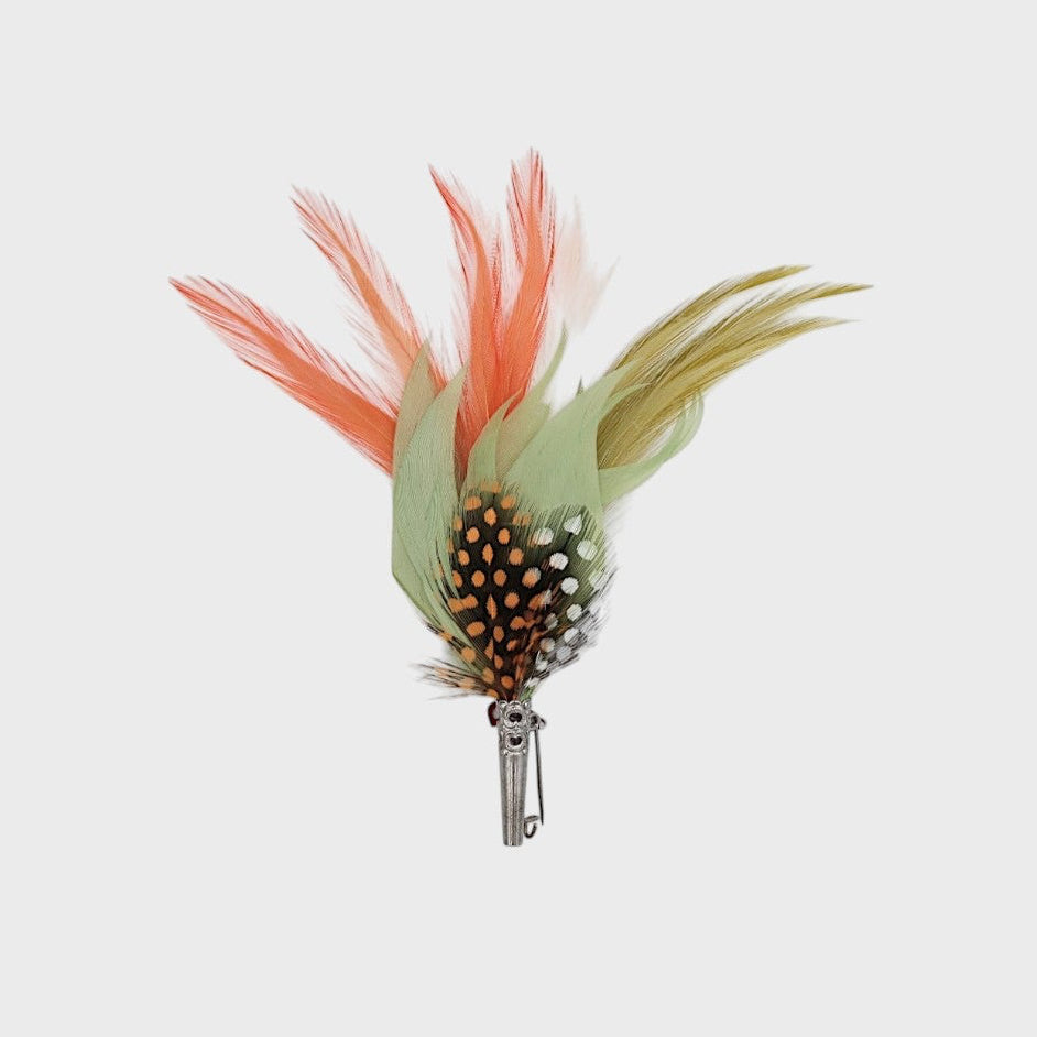 orange, green and black feathered brooch on a light gray background