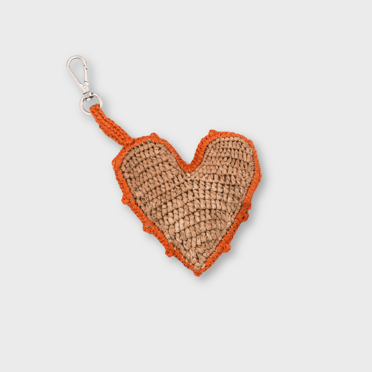 A heart-shaped raffia keychain in natural tan with an orange border and handle, attached to a silver metal clasp.