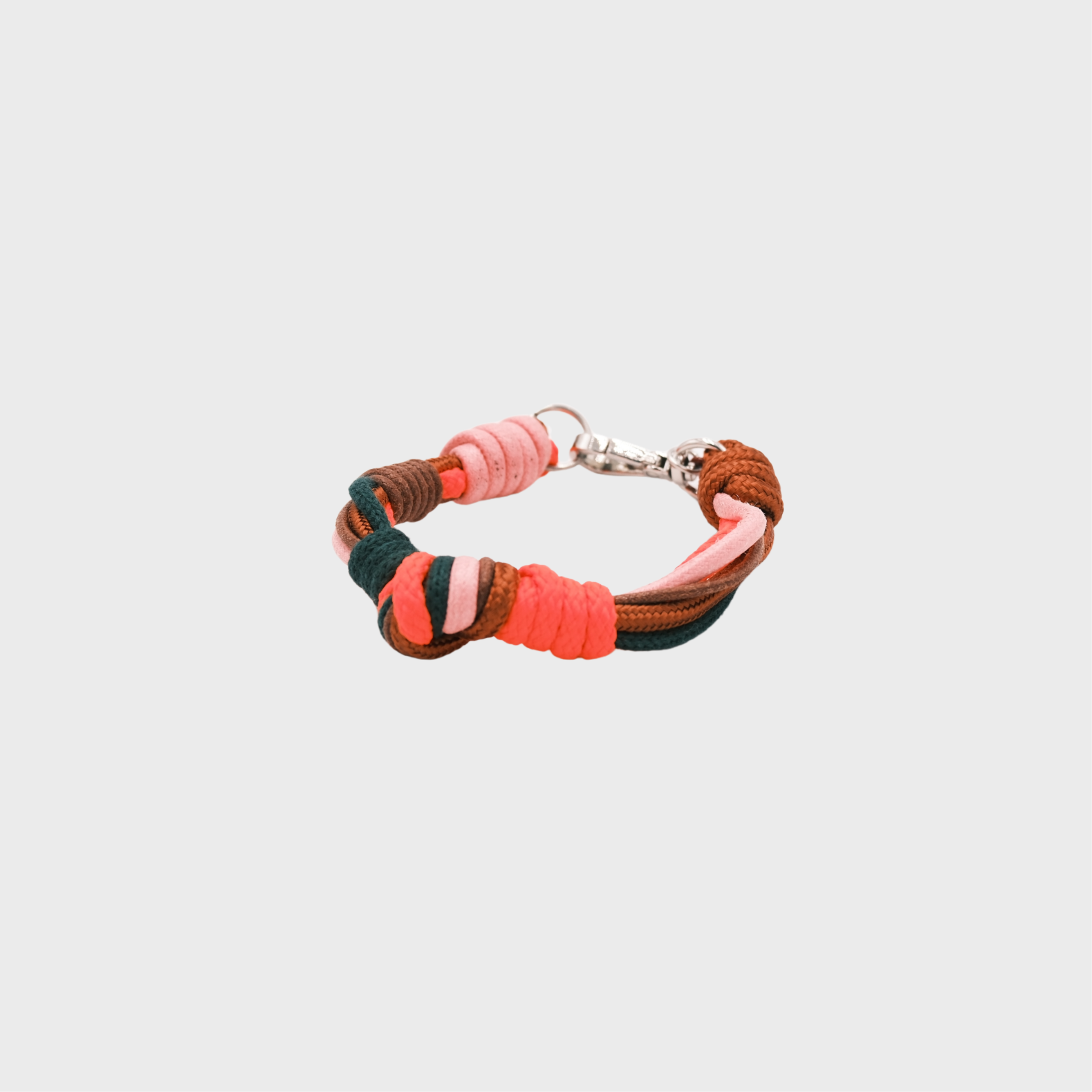 A macramé bracelet with knotted details, featuring shades of neon orange, green and brown, finished with a silver-tone metal clasp, set on a light gray background.