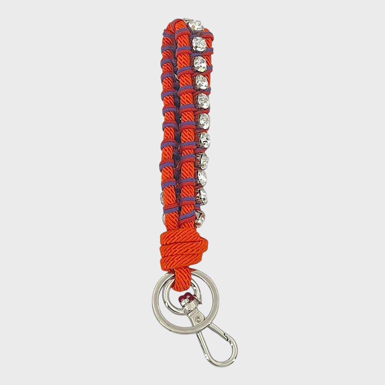 A macramé braided keychain strap featuring a orange, purple and red, accented with a vertical row of silver rhinestones, and finished with a silver metal lobster clasp on a light gray background.