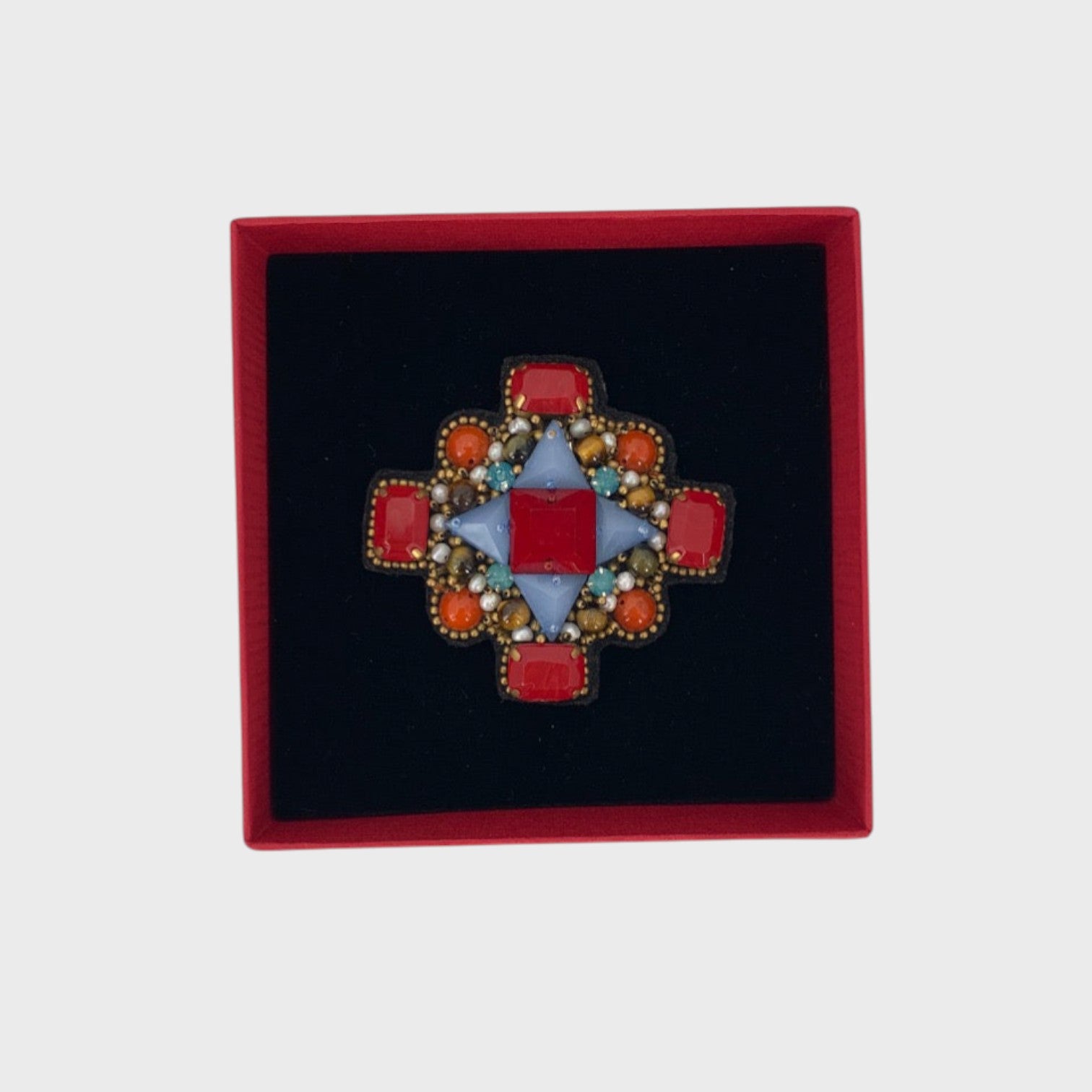 A red orthodox cross brooch on a red box. 