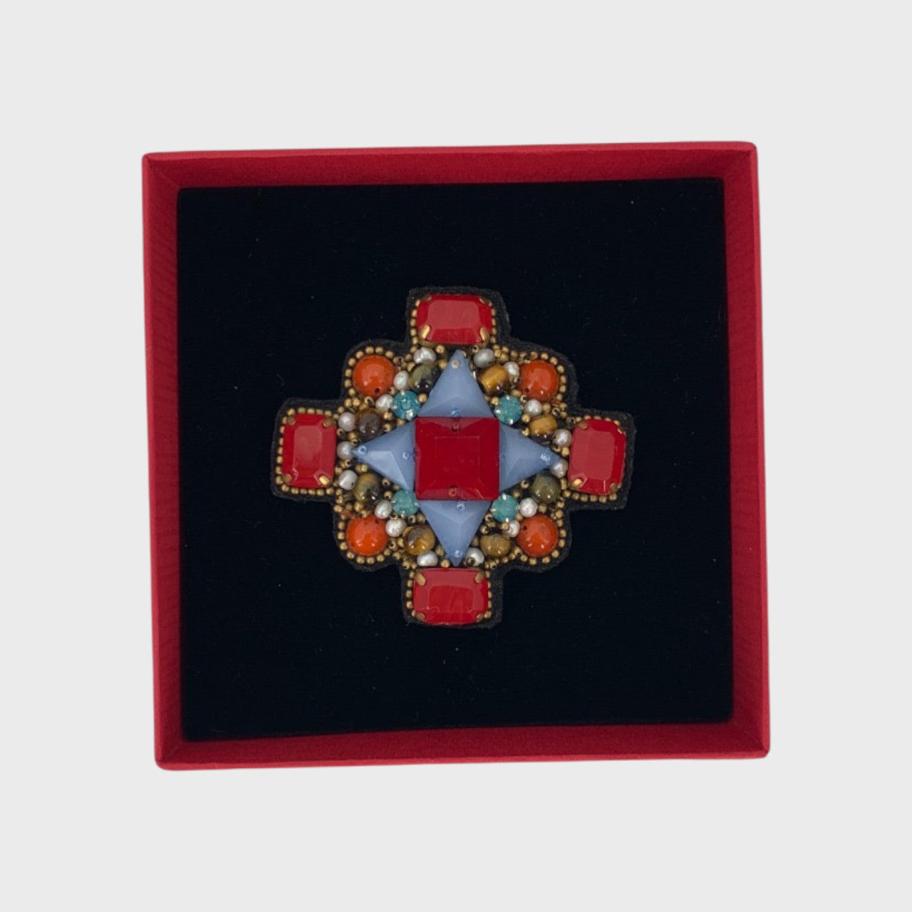 An embroidered brooch representing a red orthodox cross in a box. 