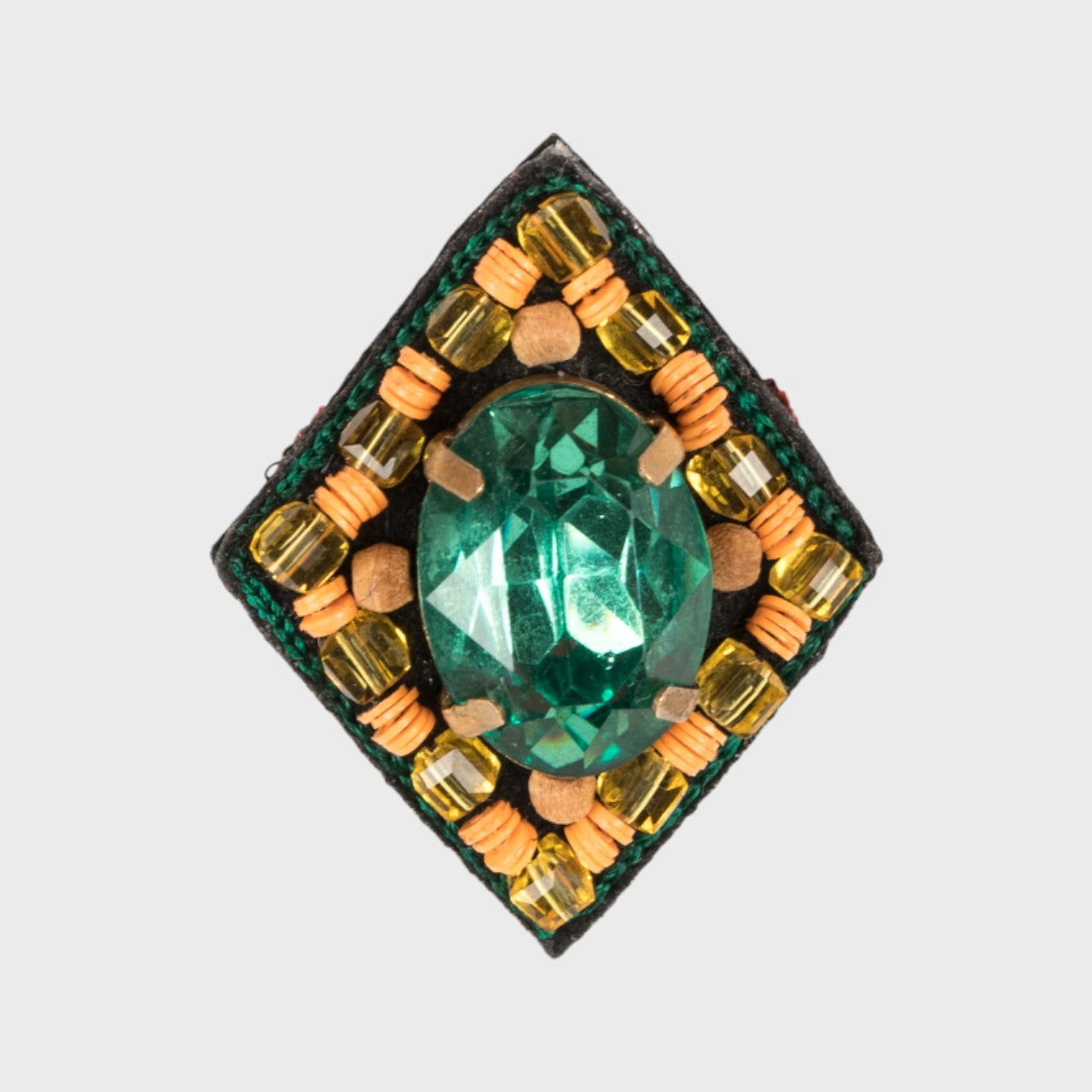 An oval embroidered brooch in green with a green stone middle. 