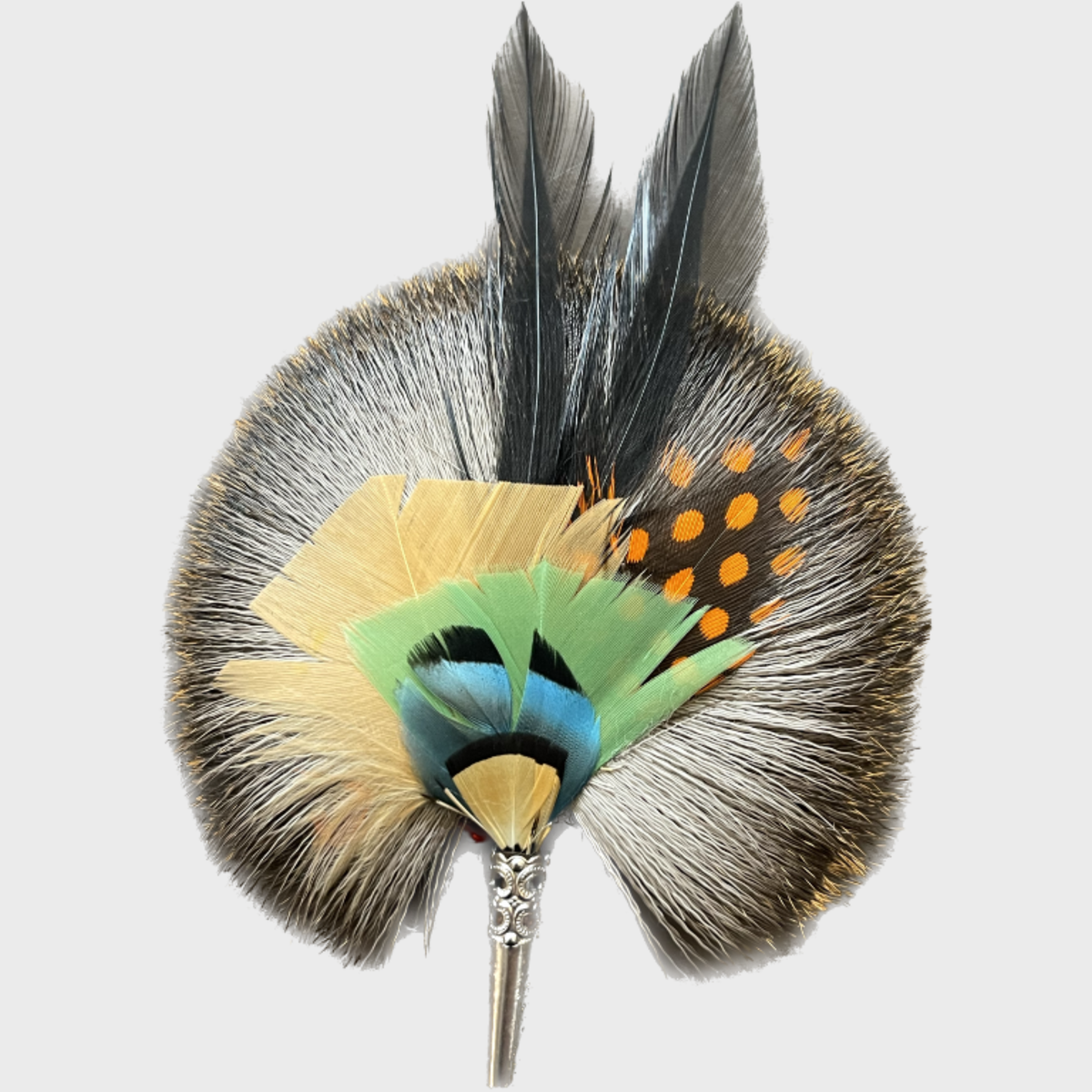 A round brooch featuring a collection of dyed feathers in various colors and patterns, attached to a central point with a metallic-looking hardware.