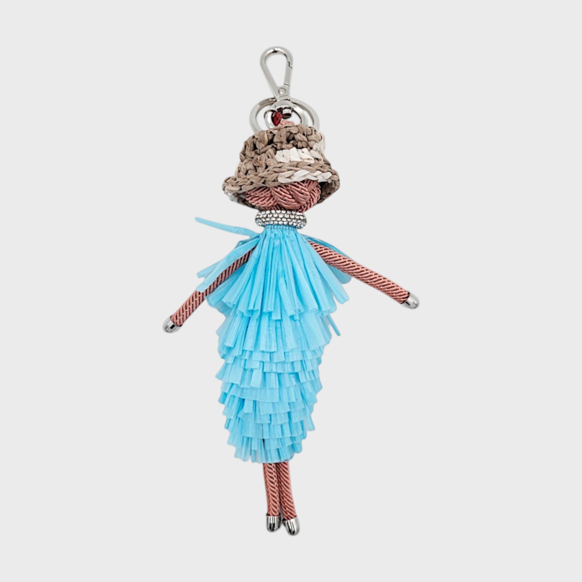 Handmade macramé bag charm featuring a character in a blue fringed layered maxi dress, a bucket hat and a bedazzled chocker necklace. She is attached to a silver clasp.