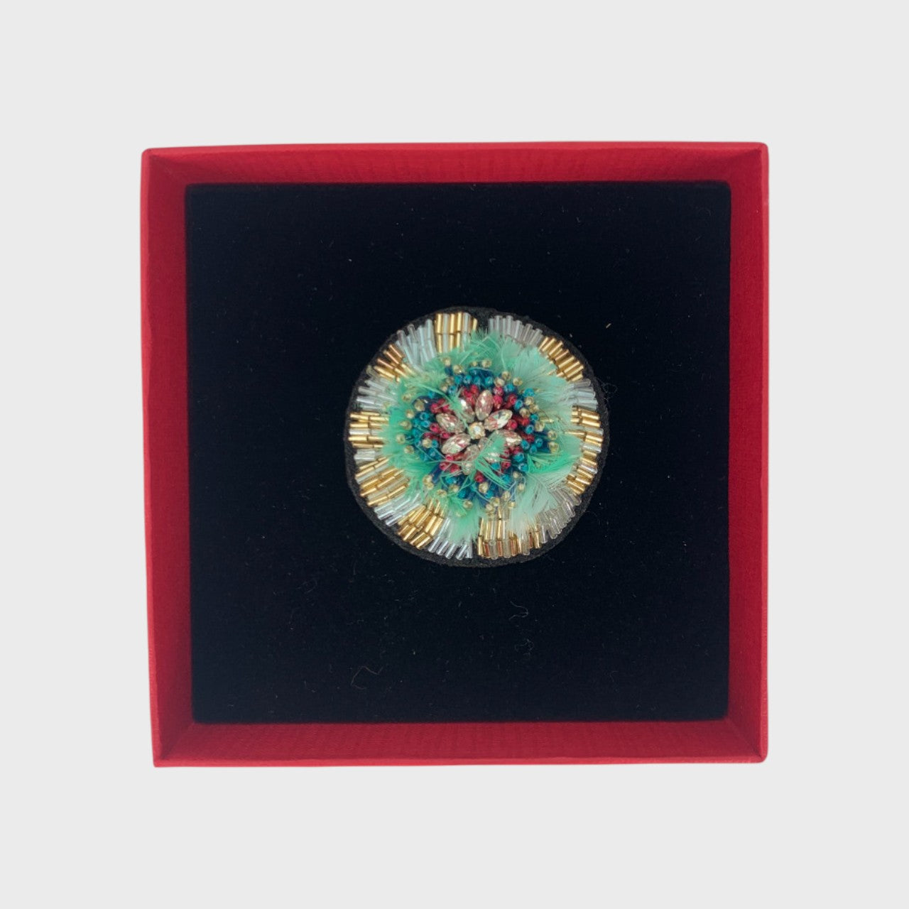 An embroidered brooch representing a blue passiflora in a box. 