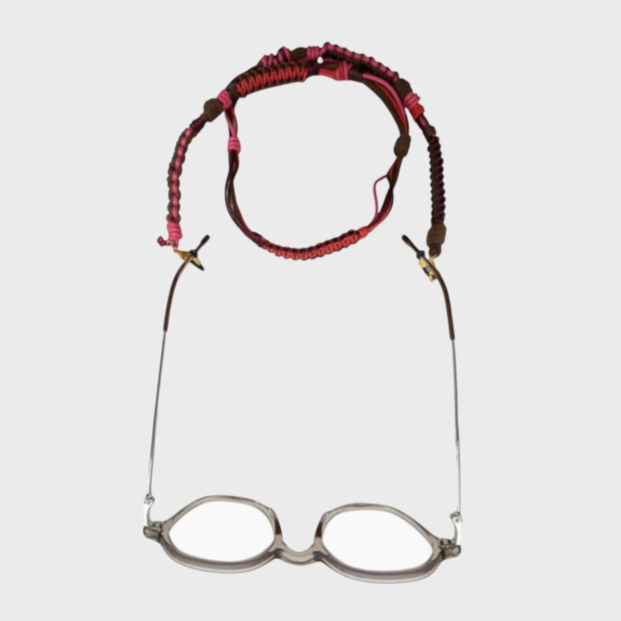 Woven eyeglass holder with red, pink and brown details on a white background