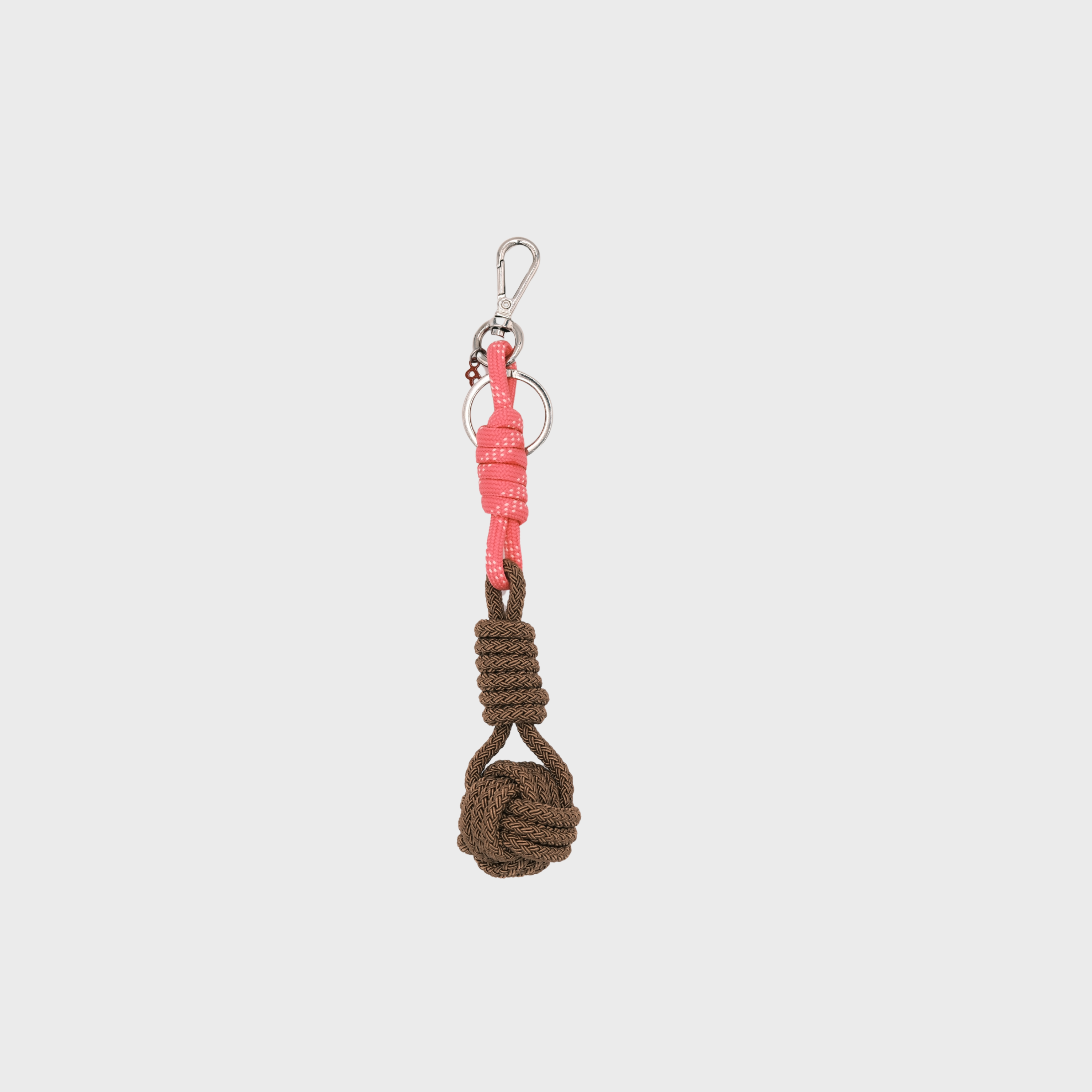 A macramé keychain representing a ball inspired by sailors knots. The straight upper part is pink and the ball part is brown. 