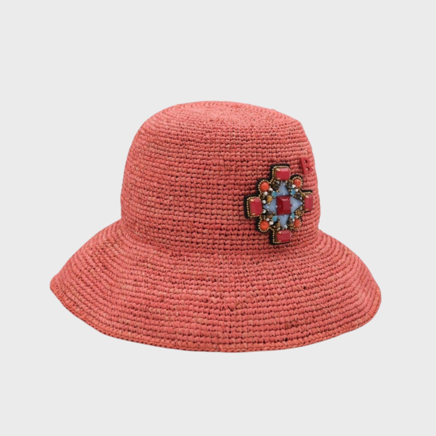 A pink raffia bob with a red orthodox cross brooch pinned on it. 