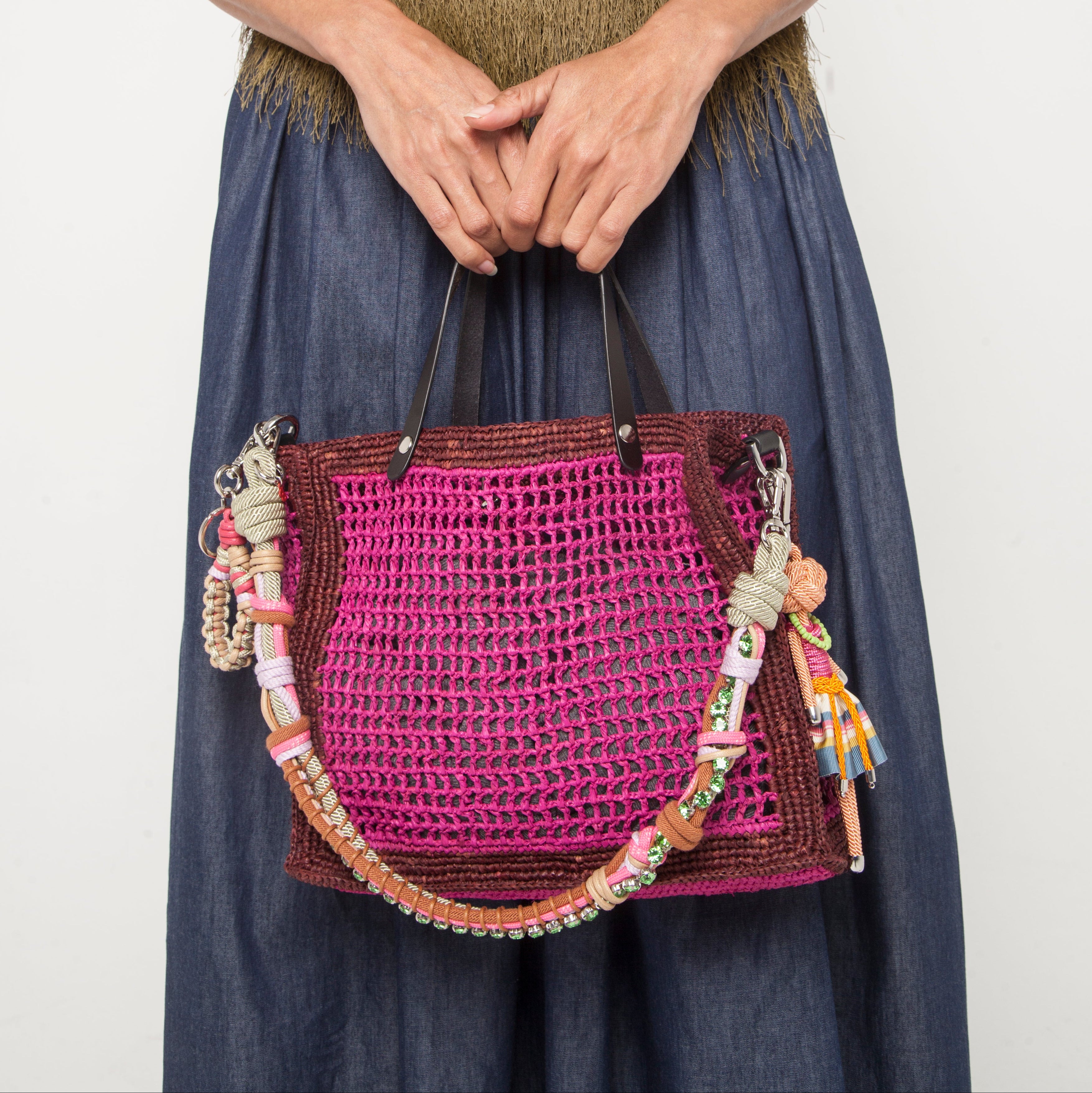A model Carrying the pink Cabas handbag with a pink and green strap and two keyrings. 
