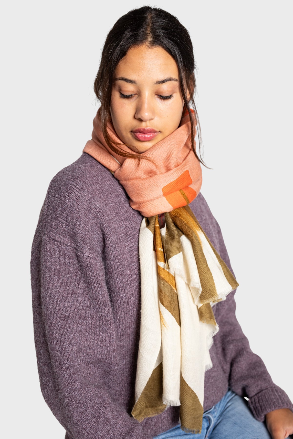 Woman wearing a patterned cashmere shawl or scarf on a plain background