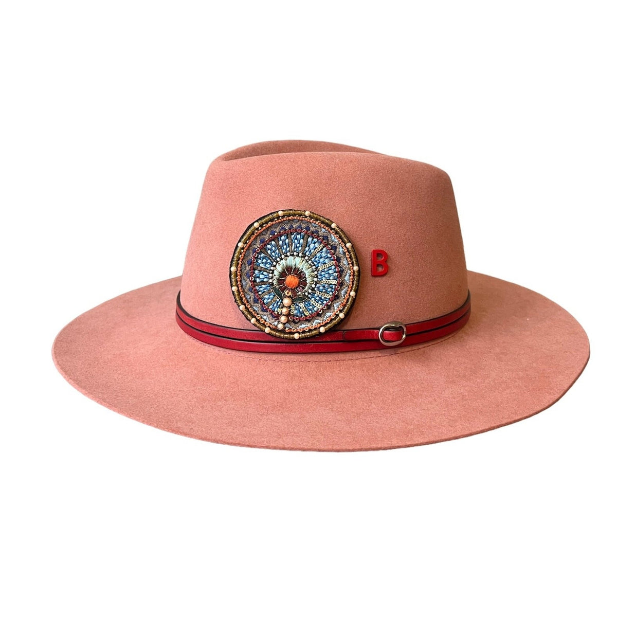A wool hat with a red double leather hat band and an embroidered circular brooch. 