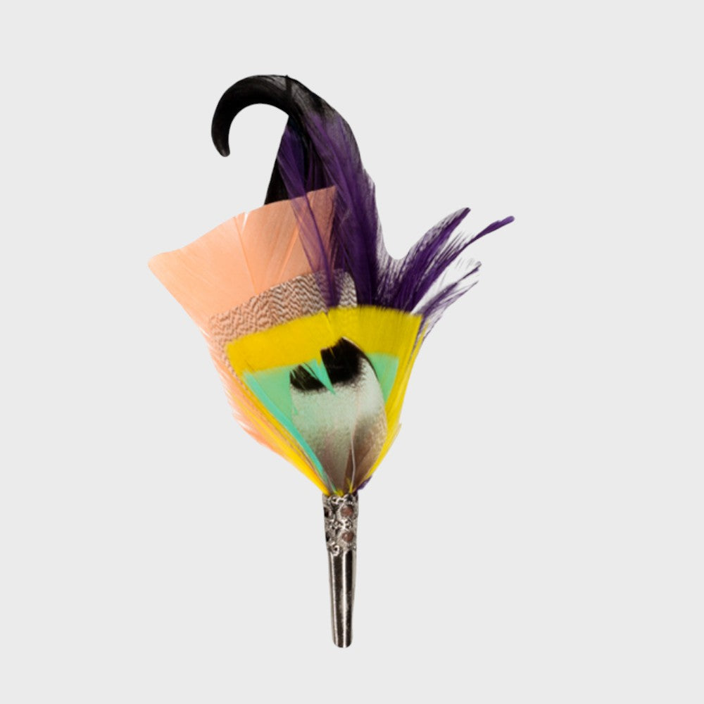 Purple, black, light pink, light green and yellow feathered brooch on a light gray background