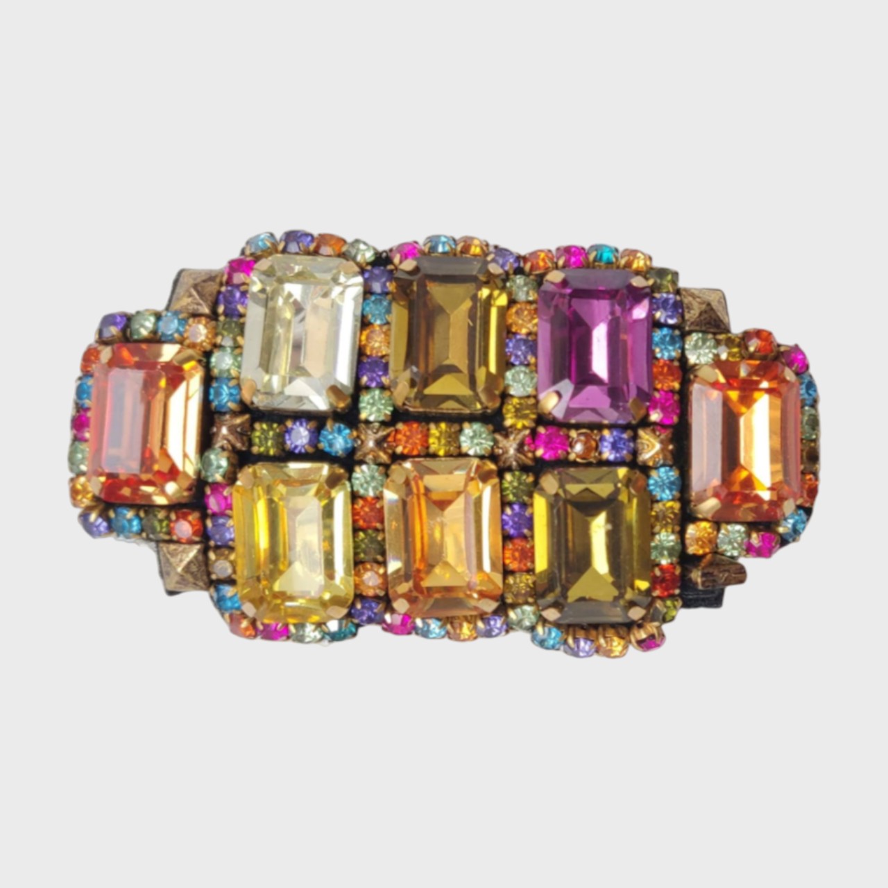 An embroidered brooch with several stones of the color of the rainbow, and smaller ones of the same colors around. 