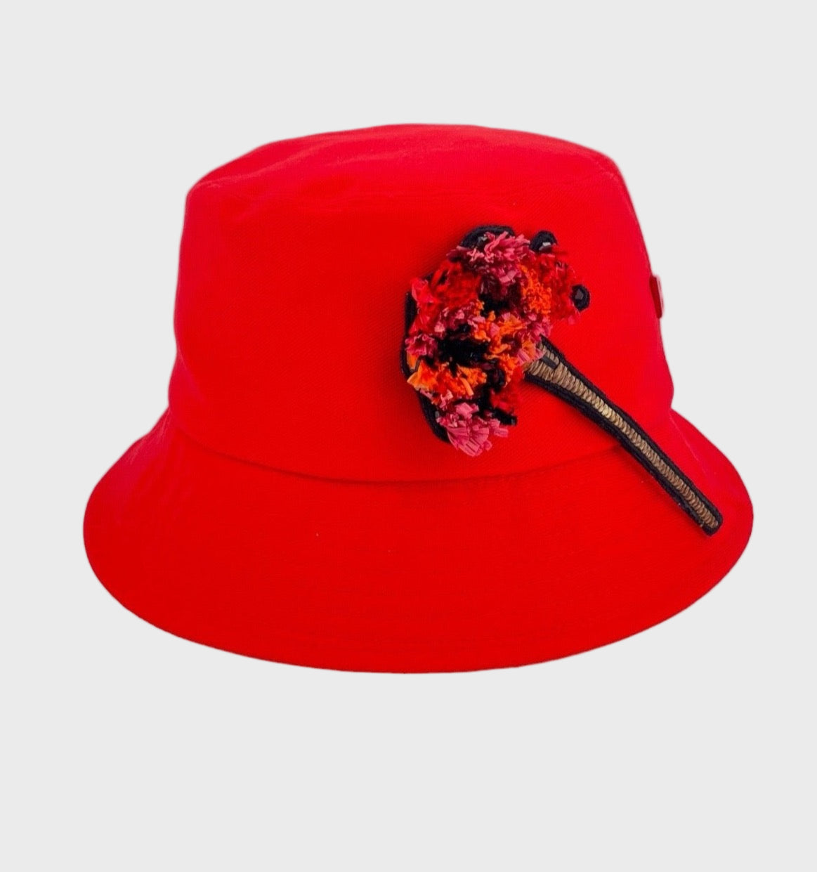 Red bucket hat with a decorative brooch on a light gray background