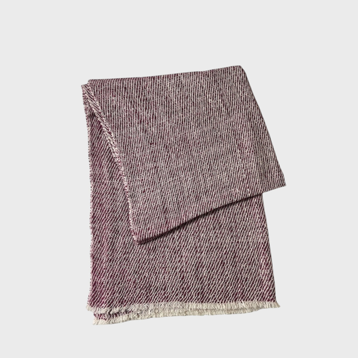 Folded red and white cashmere shawl with a subtle pattern on a light gray background