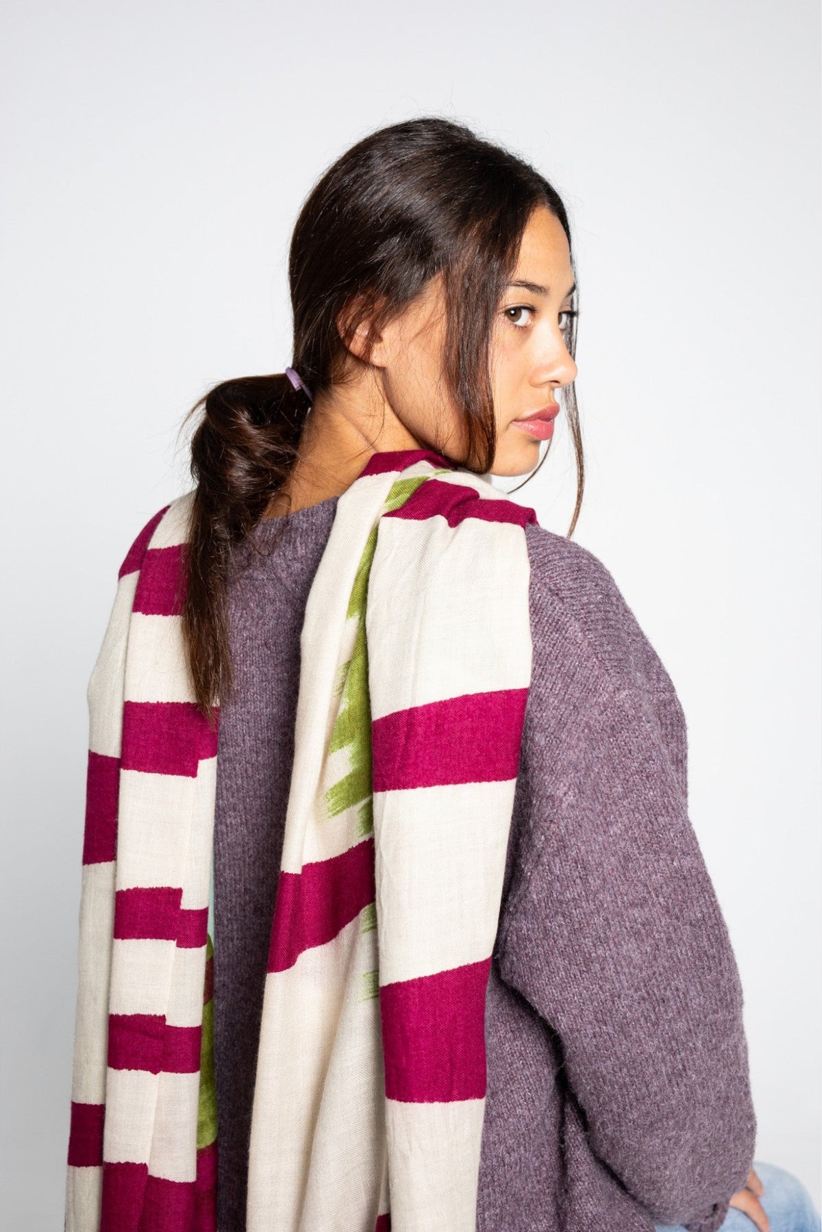 Woman wearing a colorful cashmere shawl or scarf with a plain background