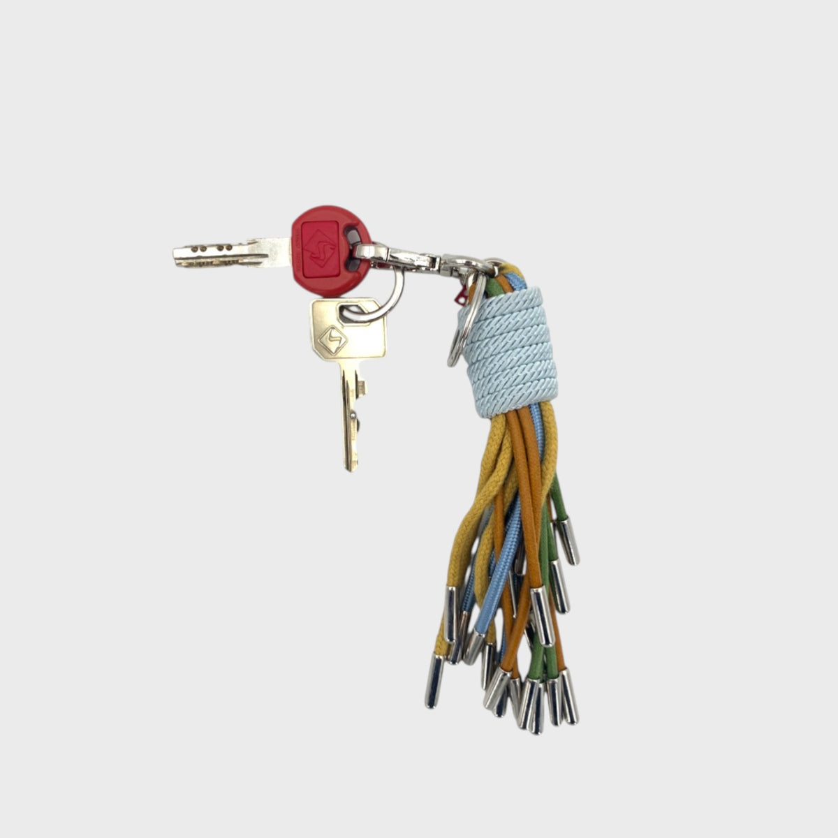 A set of keys with a Keychain with colorful tassels on a white background