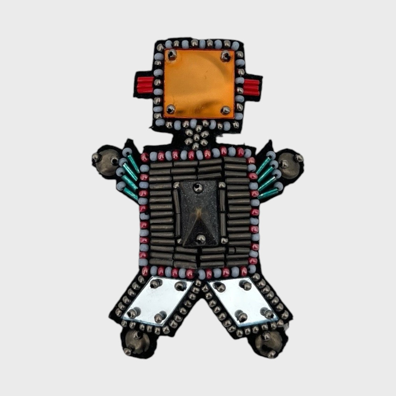 An embroidered brooch representing a grey robot, with an orange stone for the head and blue details. 