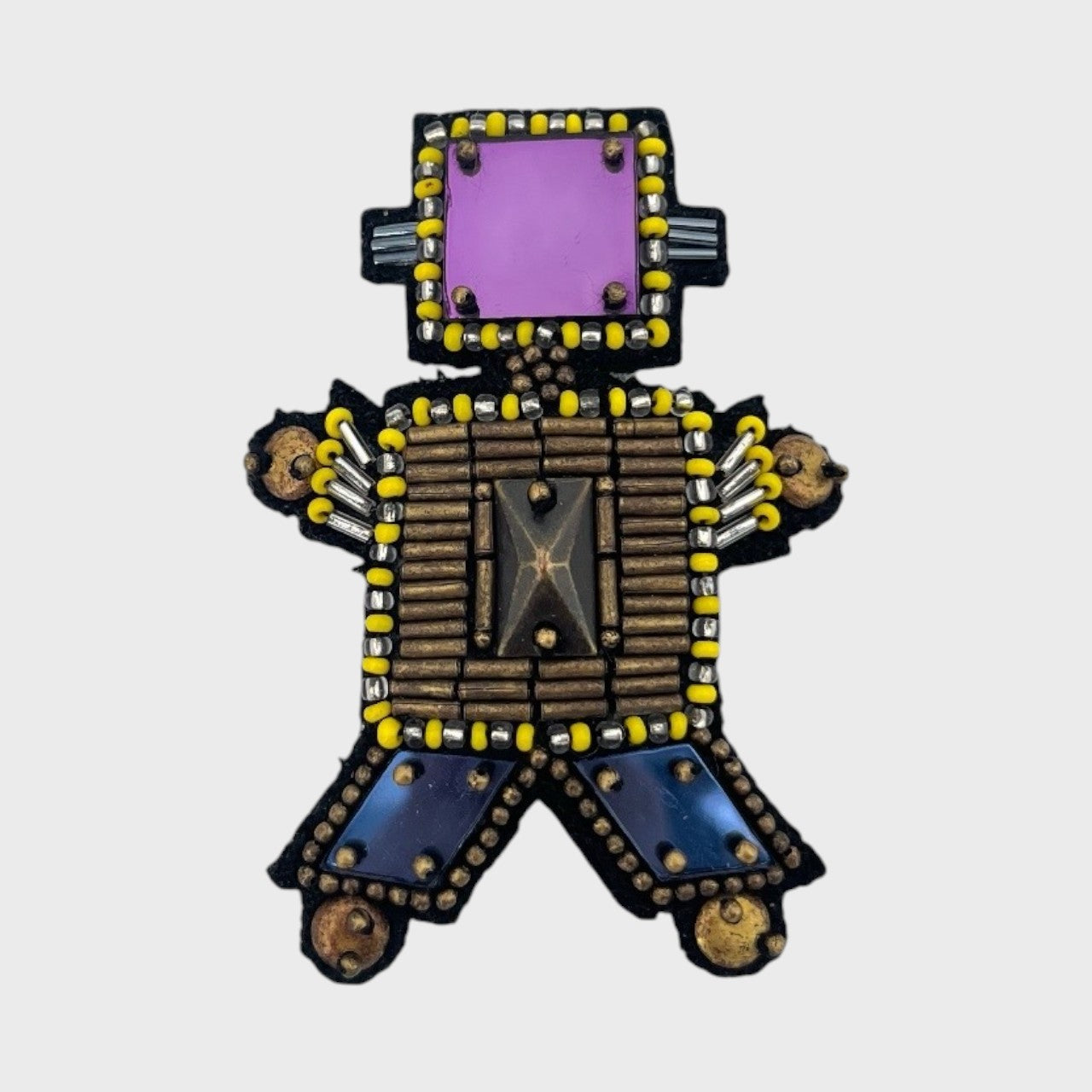 An embroidered brooch representing a bronze robot with a purple stone for the head. 