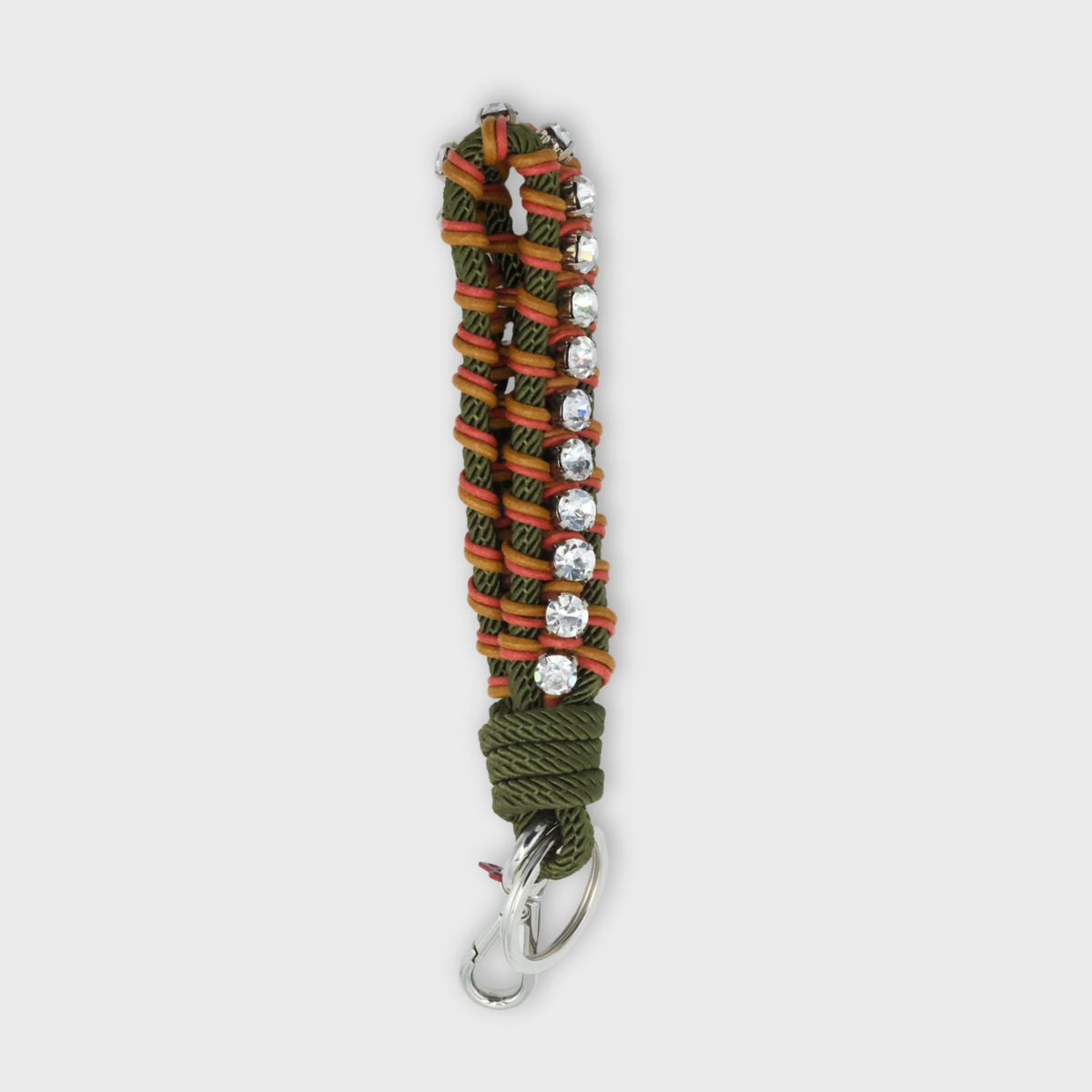 A multicolored knotted macrame key ring in green, orange and yellow with clear rhinestones on a light grey background.