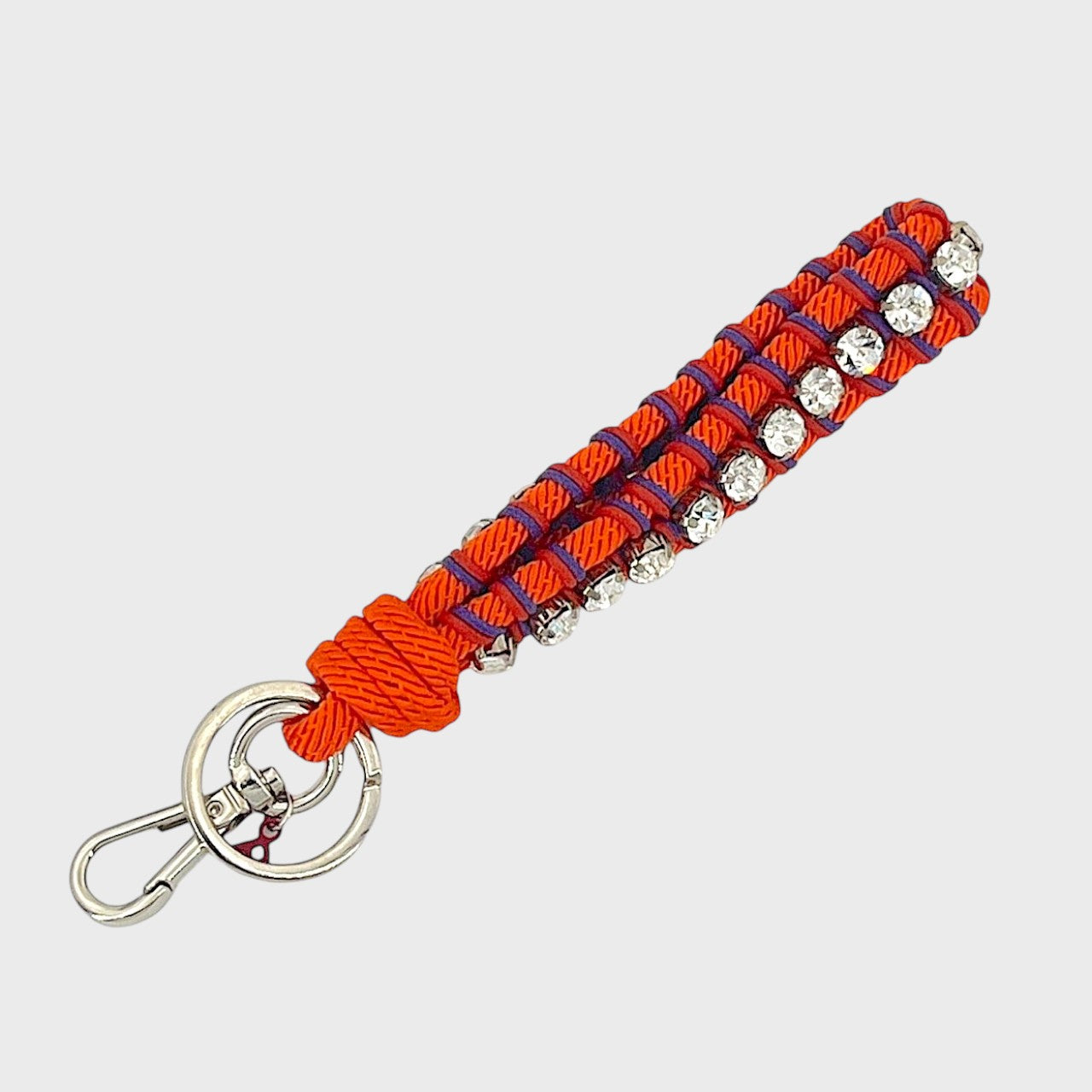 Keychain with orange, purple and red patterned band and rhinestones on a white background