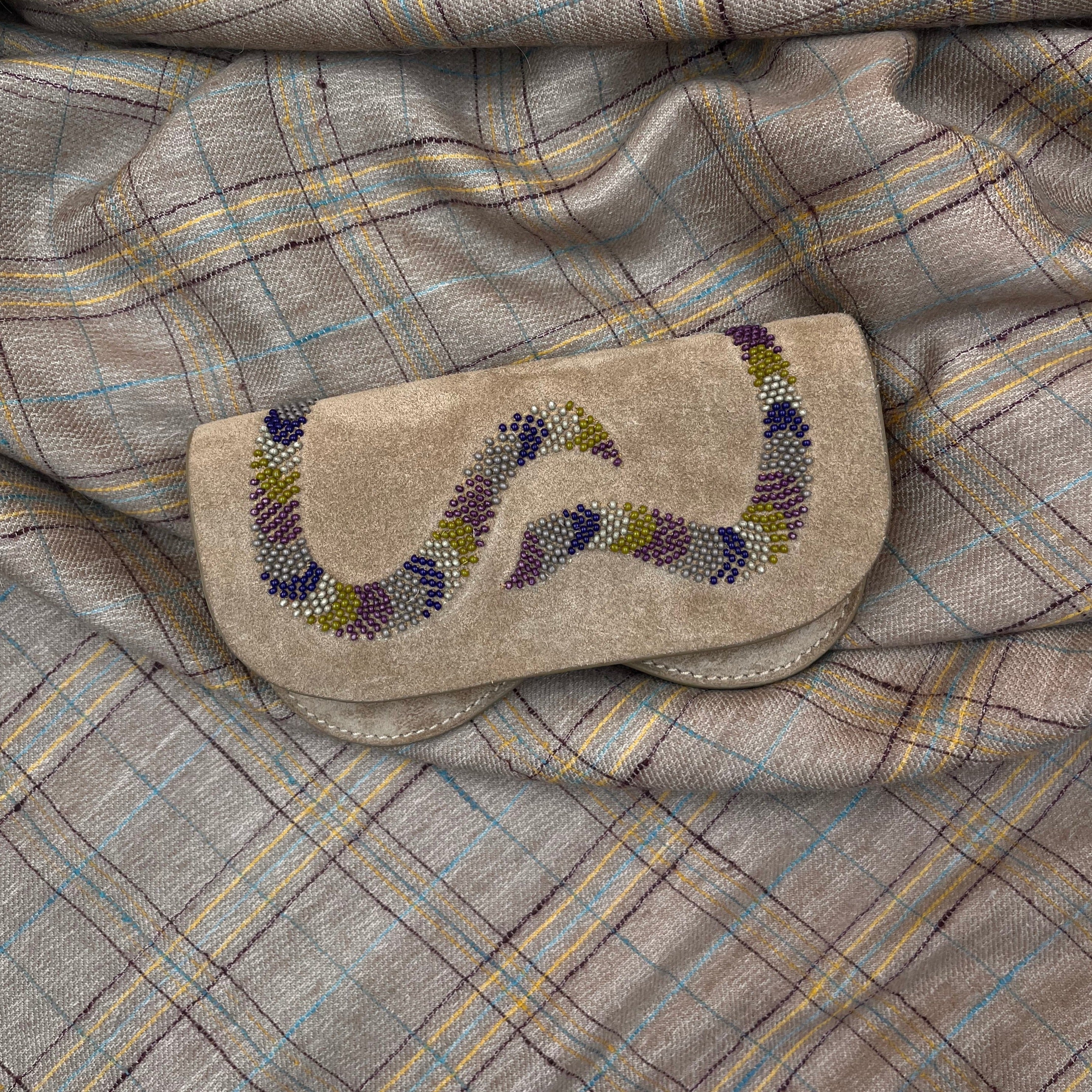 A brown suede leather Snake glasses case put on a grey blanket. 