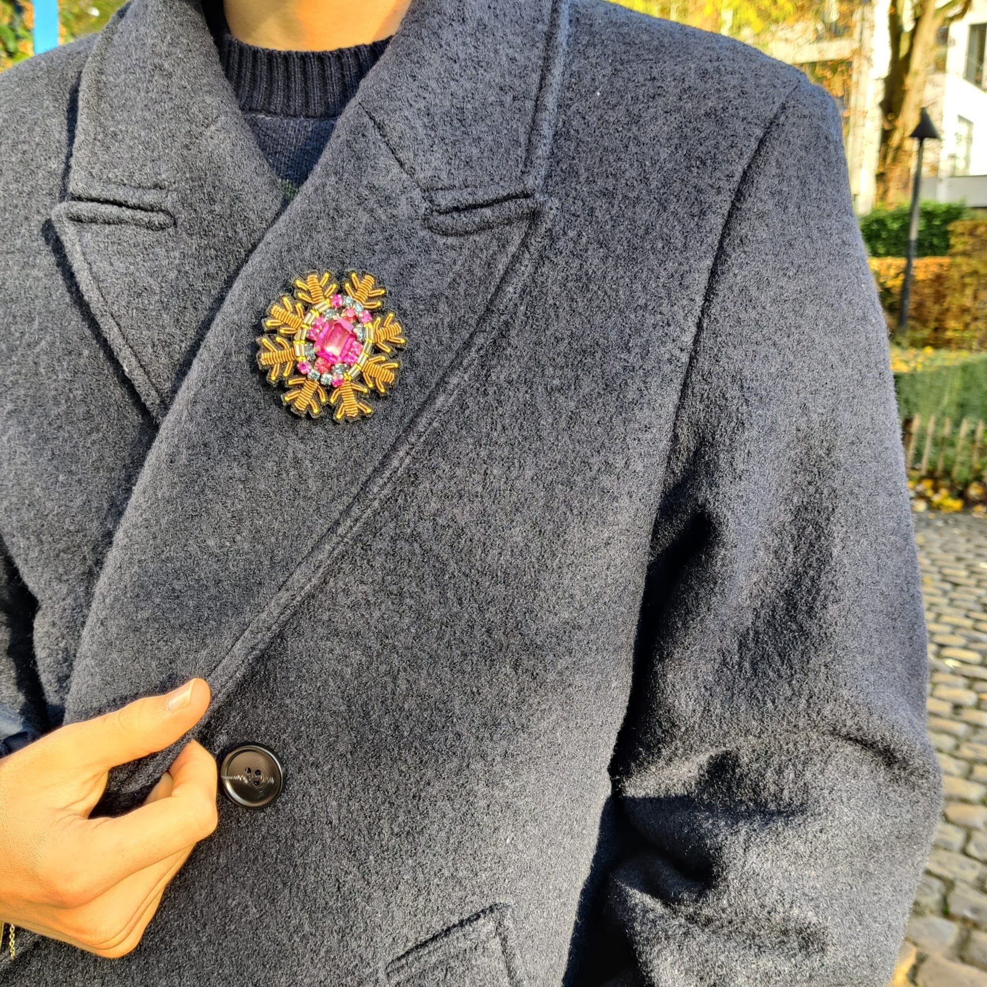 A model wearing on her coat the pink stoned center brooch representing a snowflake. 